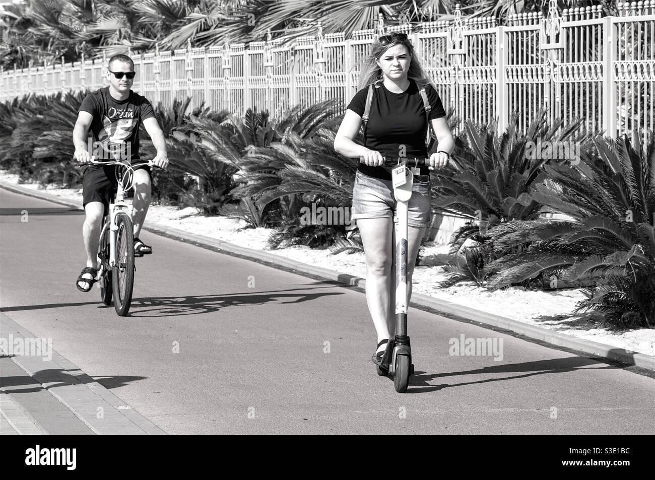 Une fille sur un scooter et un gars sur un promenade à vélo sur la piste cyclable Banque D'Images