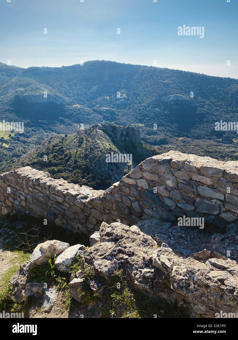 Vue panoramique d'une vallée verdoyante et d'une montagne en arrière-plan depuis les ruines des murs d'un ancien château au sommet d'une colline, en une journée ensoleillée de printemps. Banque D'Images