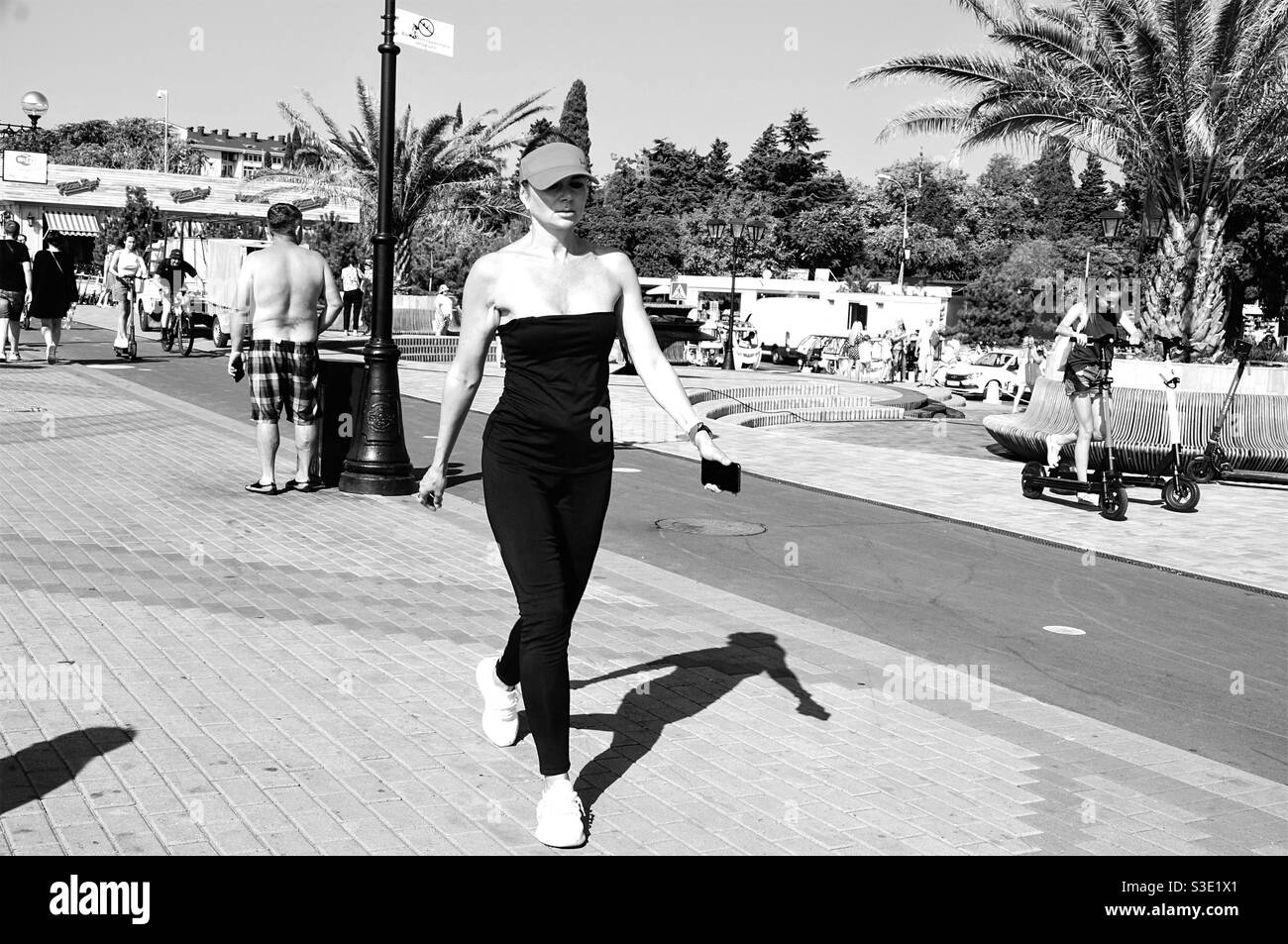 Une fille dans un chapeau marche à un rythme rapide le long de l'allée ensoleillée Banque D'Images
