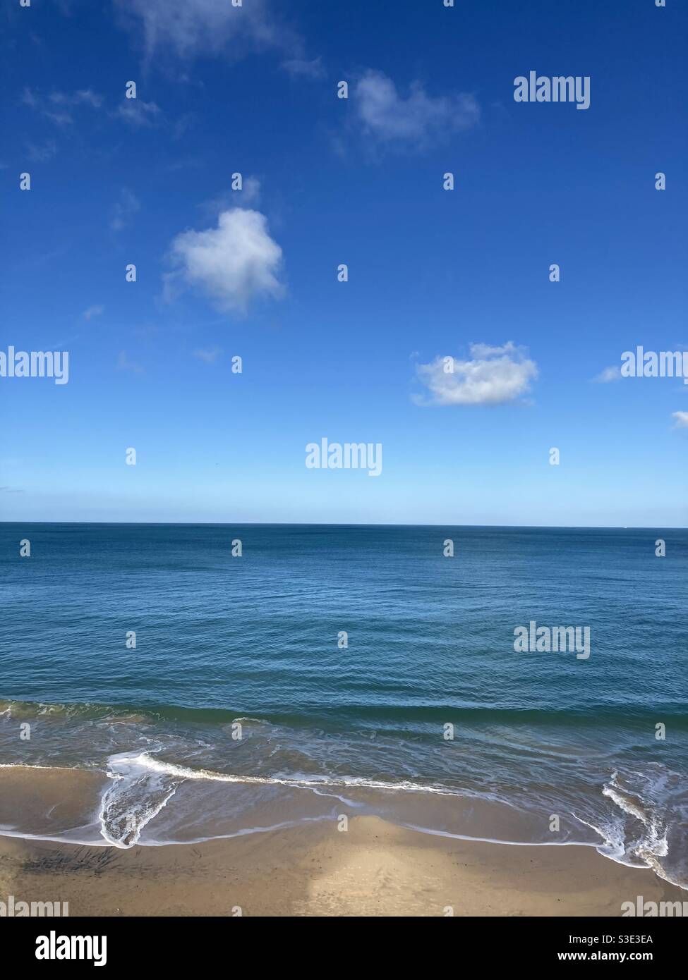 Ciel bleu, mer bleue et plage de sable avec quelques petits nuages blancs - Image de stock capturée avec un smartphone