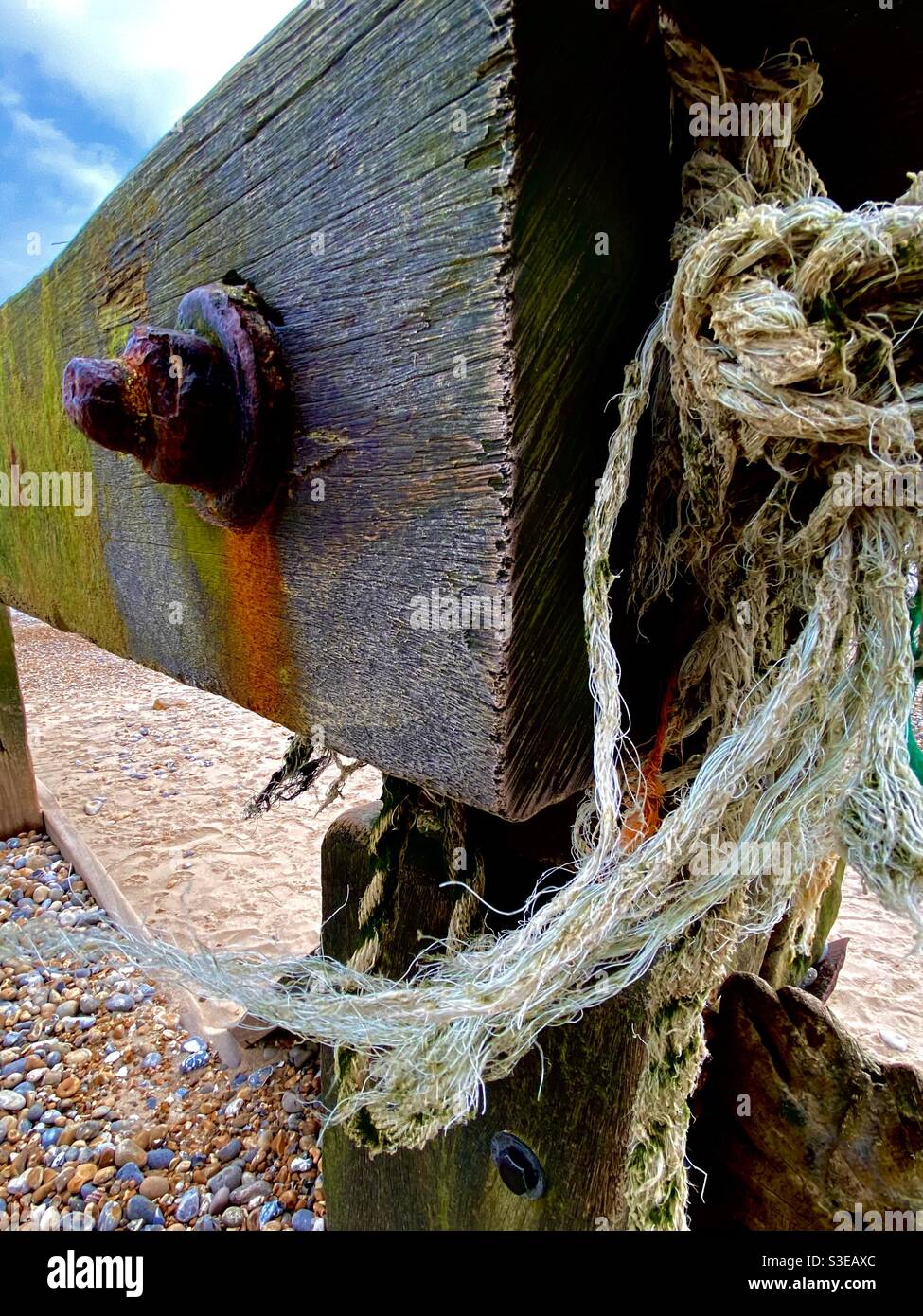 Bois de plage Groyne avec poteau à boulonner rouillé avec le vent corde déchiquetée balayée Banque D'Images