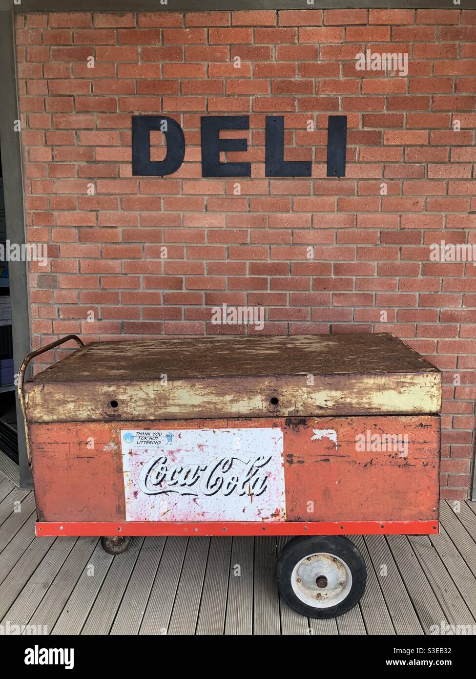 Chariot avec un panneau Coco cola contre un mur de briques Et à l'extérieur d'un deli sans nom Banque D'Images Chariot avec un panneau Coco cola contre un mur de briques Et à l'extérieur d'un deli sans nom Banque D'Images