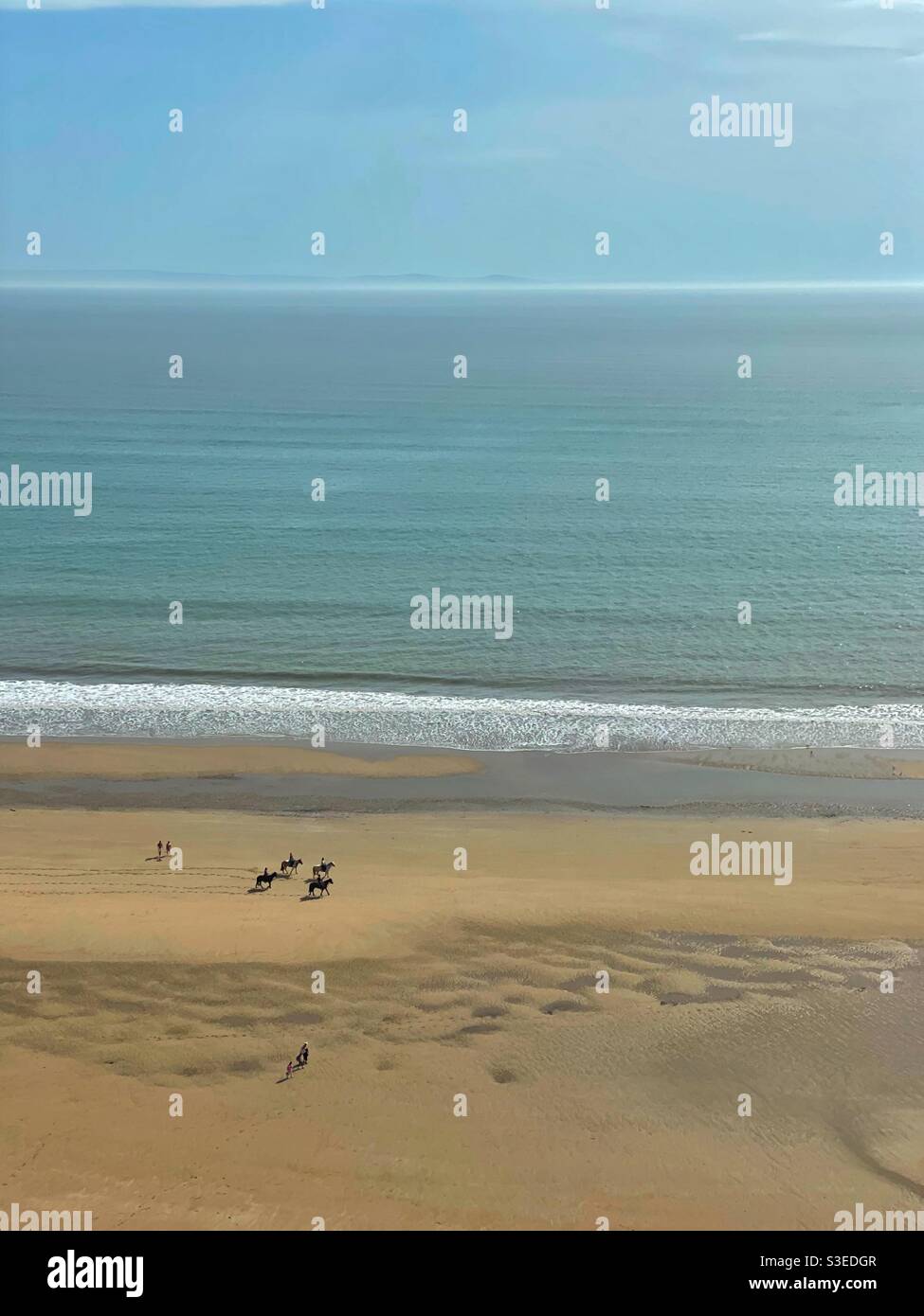 Cavaliers et marcheurs sur Three Cliffs Bay, Gower, pays de Galles du Sud, marée basse, mars. Banque D'Images