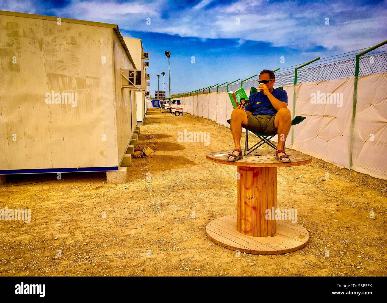 L'homme s'est assis à la chaise sur le tambour de câble dans le camp de désert - Image de stock capturée avec un smartphone
