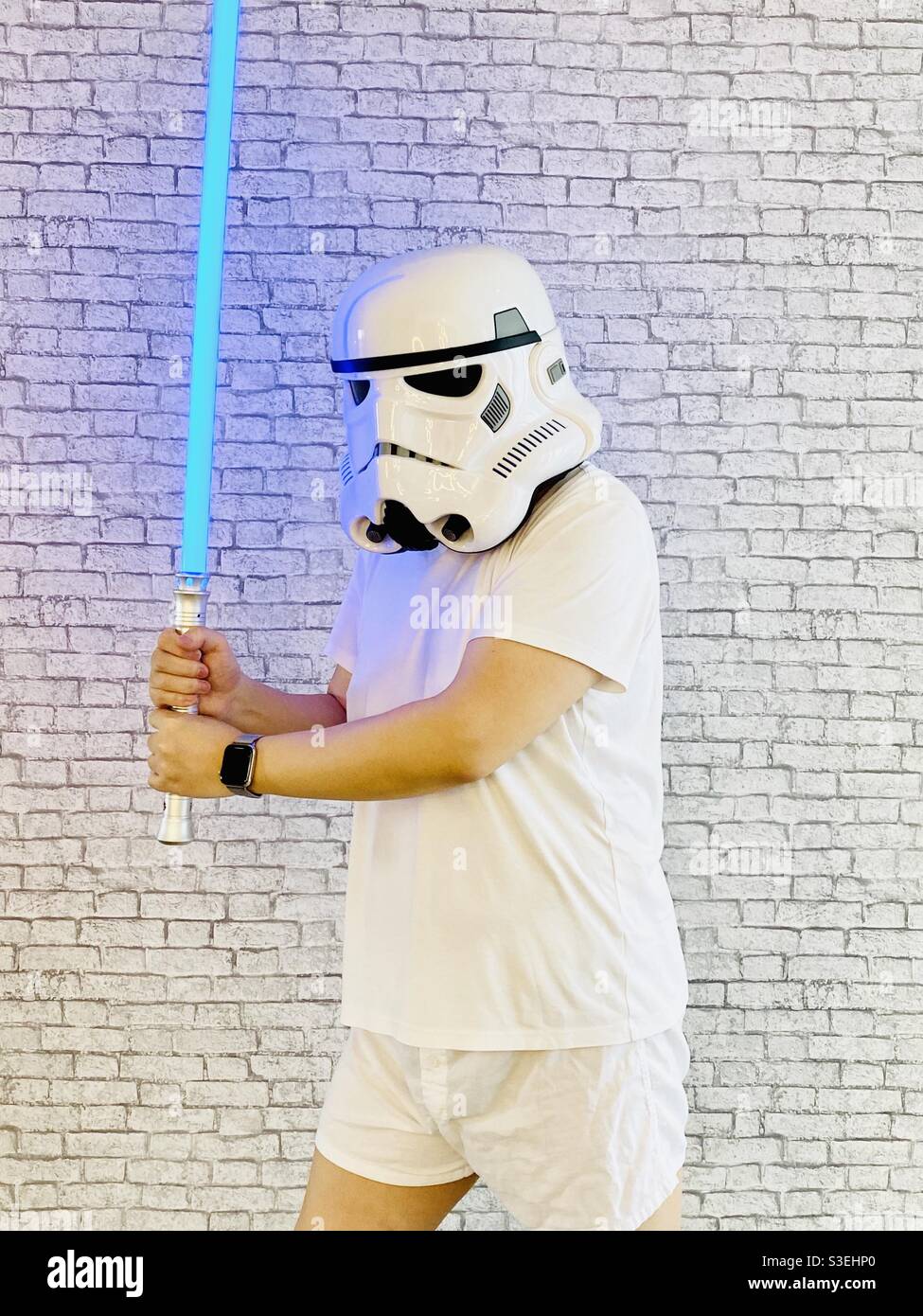 Fanboy de Star Wars jouant l'épée laser avec un casque de stormtrooper  devant le mur blanc Photo Stock - Alamy