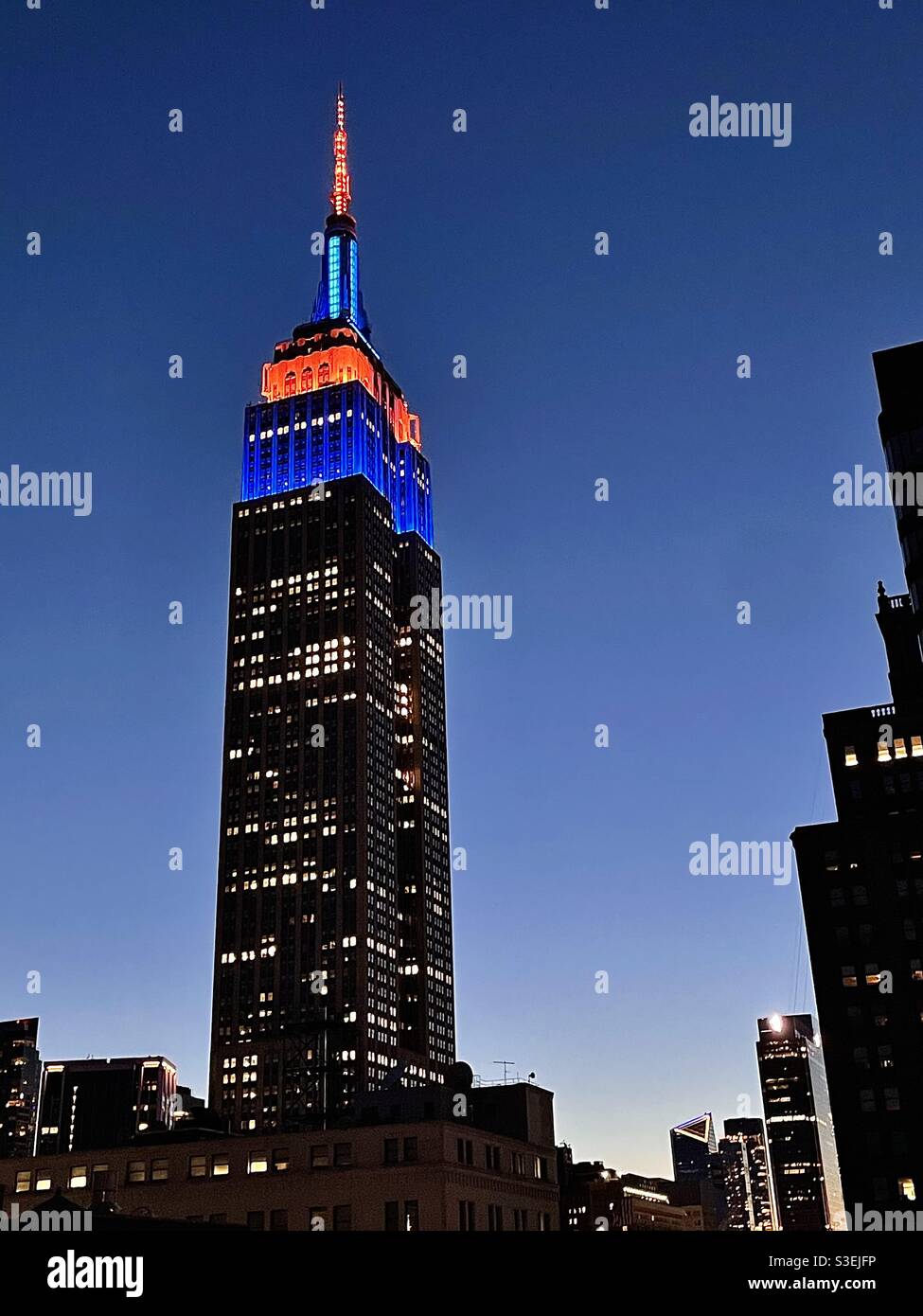 Lumières de la tour bleue et orange sur le bâtiment EmpireState en l'honneur du jour d'ouverture des mets de New York ! - Image de stock capturée avec un smartphone