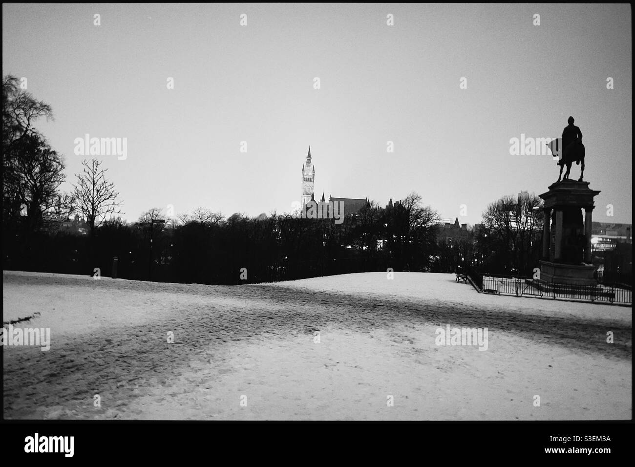 Vue sur le parc Kelvingrove en direction de la flèche de l'université de Glasgow la nuit en hiver avec de la neige au sol. Banque D'Images