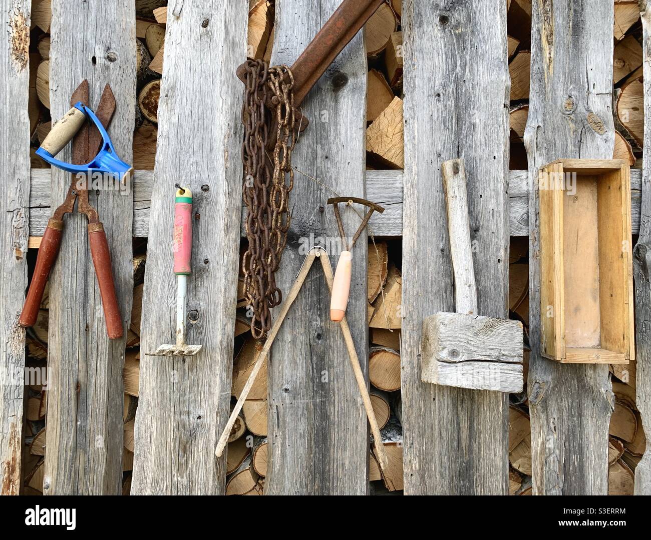 Vieux outils accrochés sur un mur en bois dans un environnement rural Banque D'Images