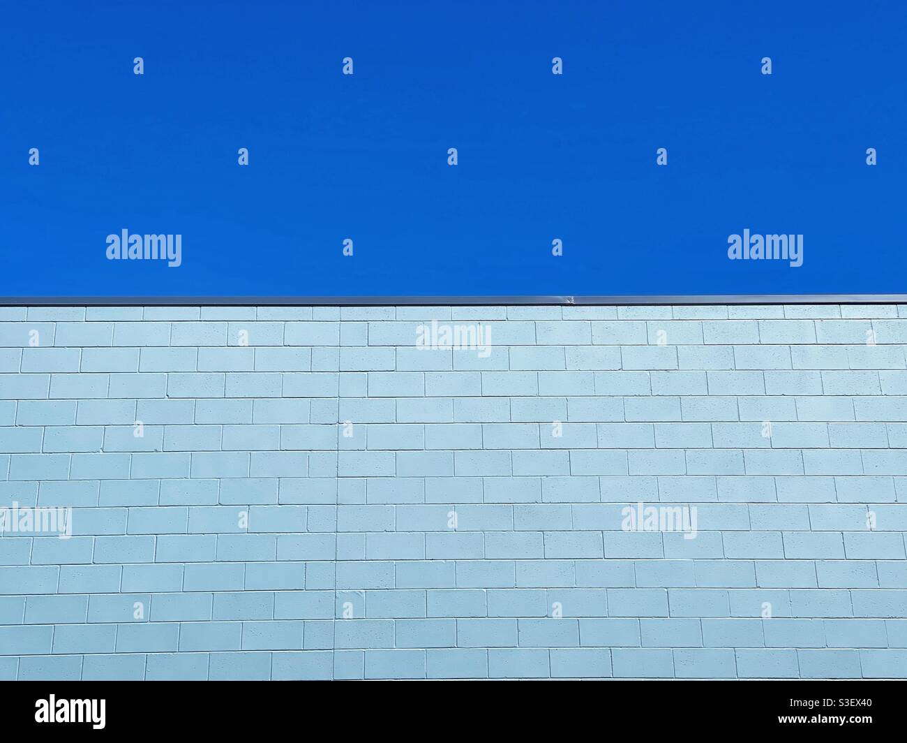 Mur de briques peint en bleu contre le ciel bleu - Image de stock capturée avec un smartphone