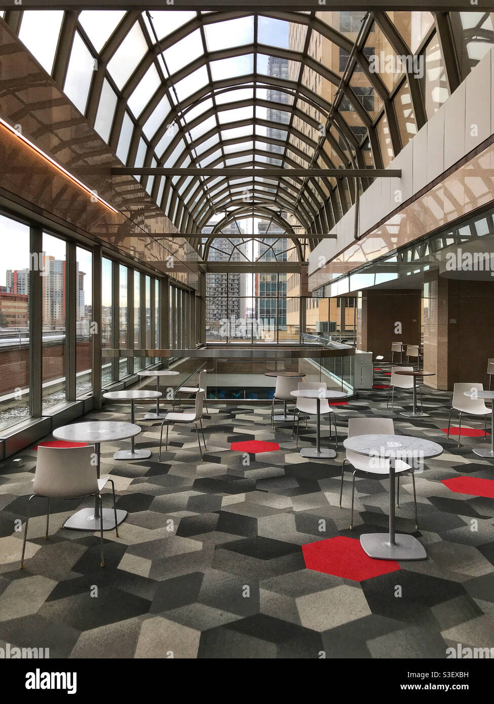 Coin salon vide avec tables socialement distancées, dans un immeuble de bureaux du centre-ville déserté, à Calgary, Alberta, Canada. - Image de stock capturée avec un smartphone