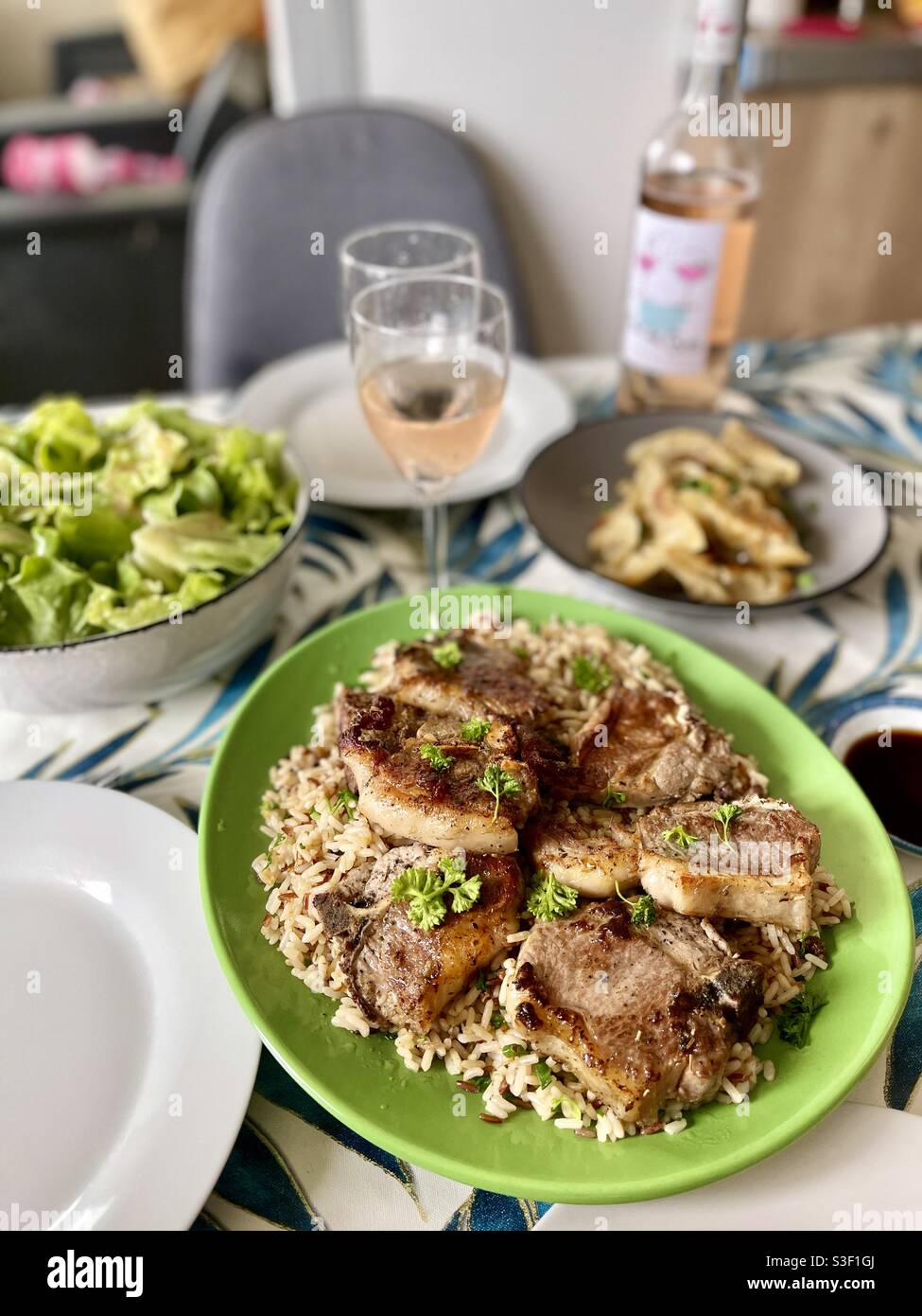 Côtelettes d'agneau sur du riz sauvage avec accompagnement de salade et vin blanc - Image de stock capturée avec un smartphone