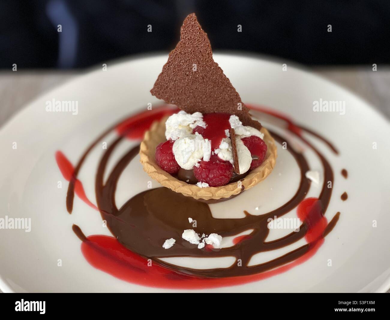 Tarte aux framboises et à la crème avec biscuit et chocolat sauce au coulis aux fraises et aux baies désertiques Banque D'Images