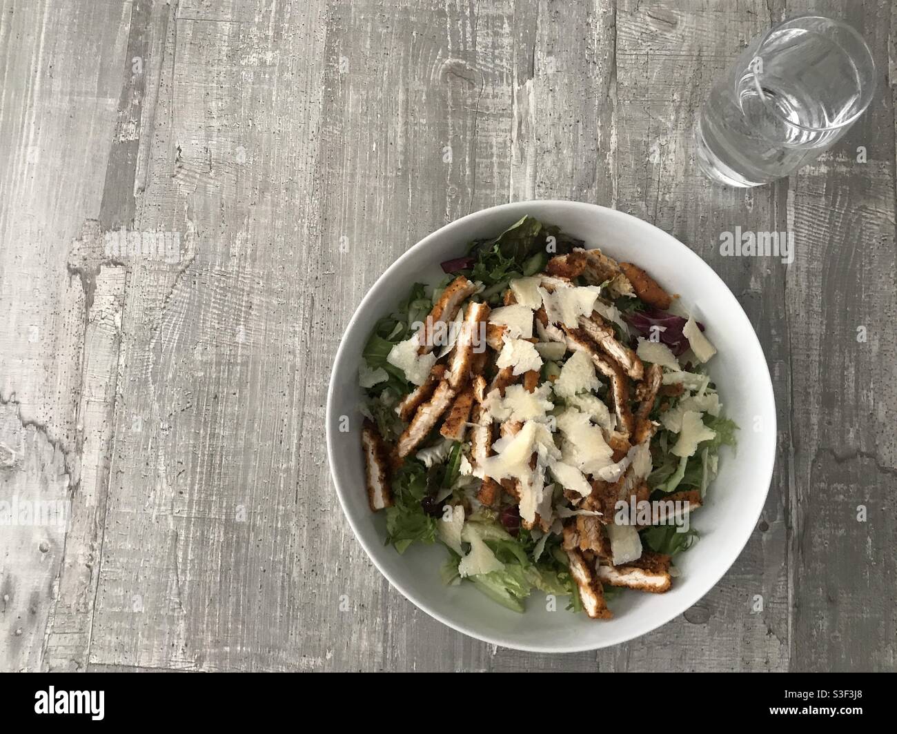 Salade de schnitzel de poulet nappée de copeaux de parmesan un fond en bois Banque D'Images