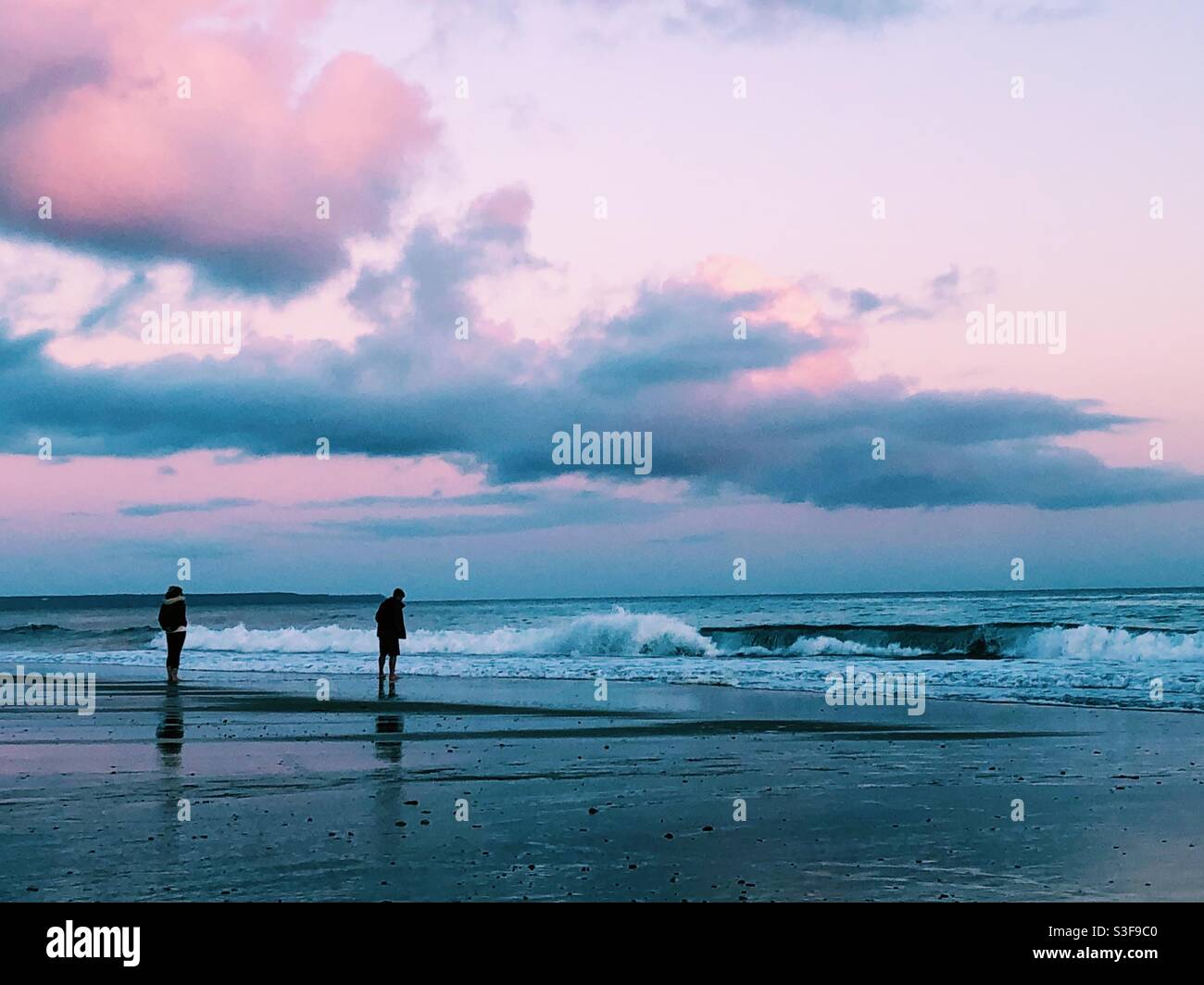 Couple silhoueté sur la plage au coucher du soleil à Cornwall Banque D'Images