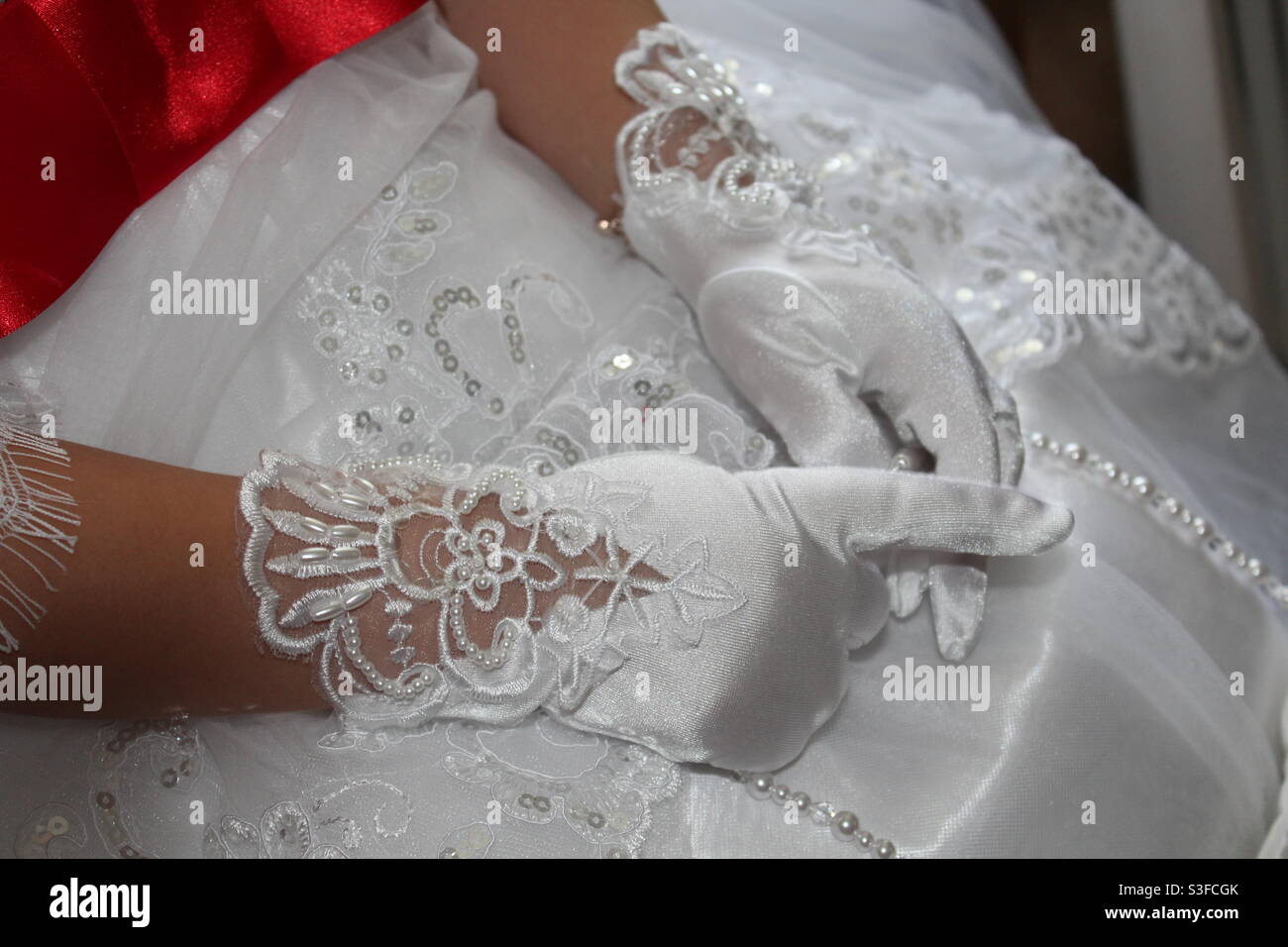 Gants en dentelle blanche sur une robe blanche avec dentelle et perles et  une ceinture rouge Photo Stock - Alamy