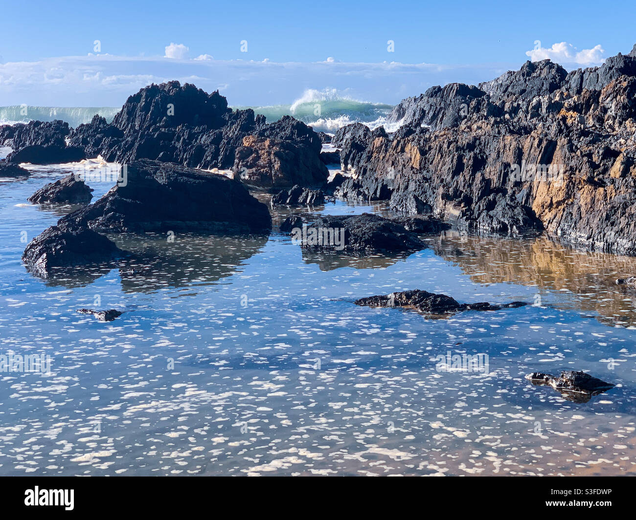 Une eau de mer étincelante et vivivivivivivivivace avec de petites pièces de mousse sur le dessus des piscines rocheuses de la plage, Sawtell Australia Banque D'Images