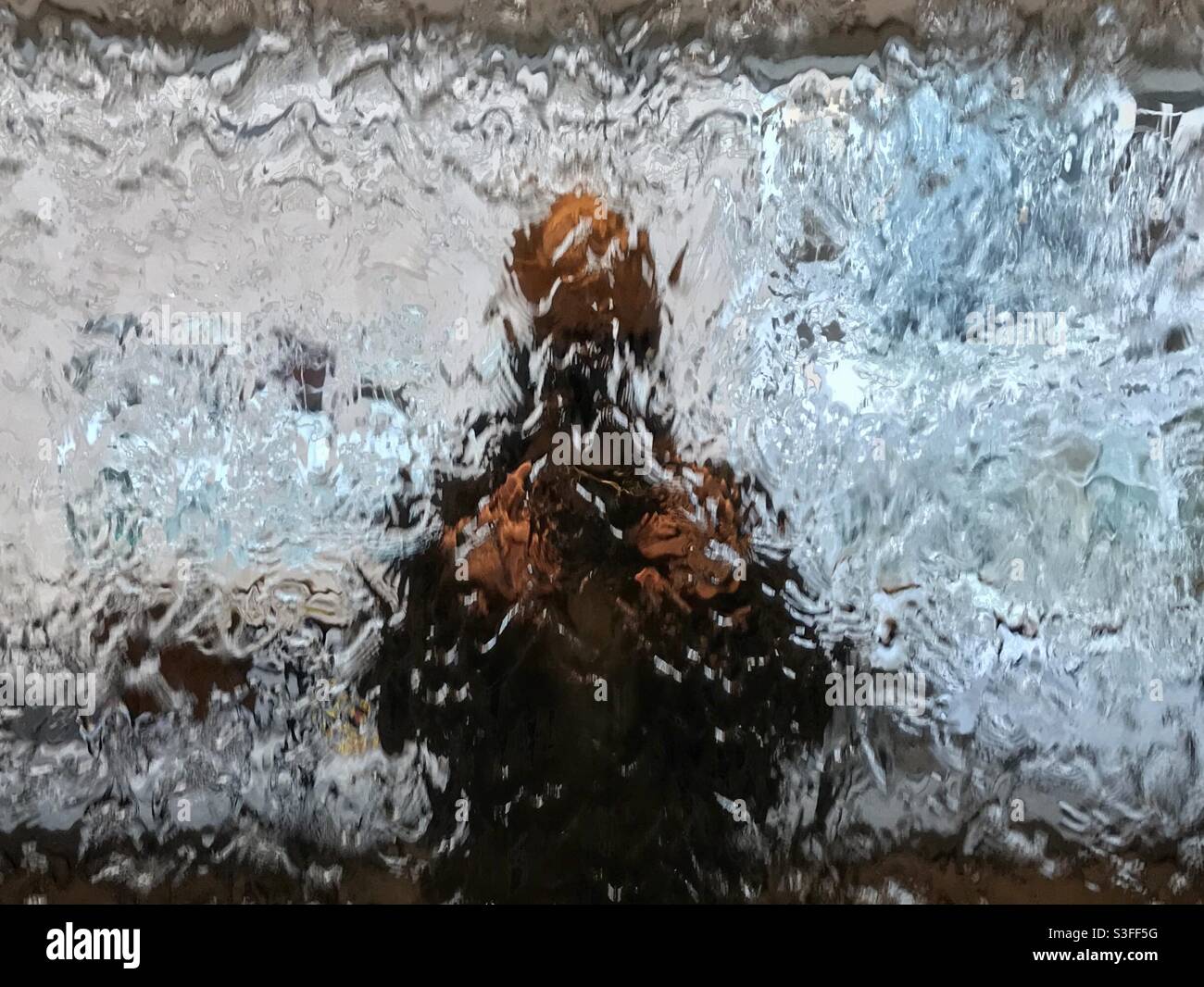 Réflexion floue d'une personne dans un mur d'eau. Banque D'Images