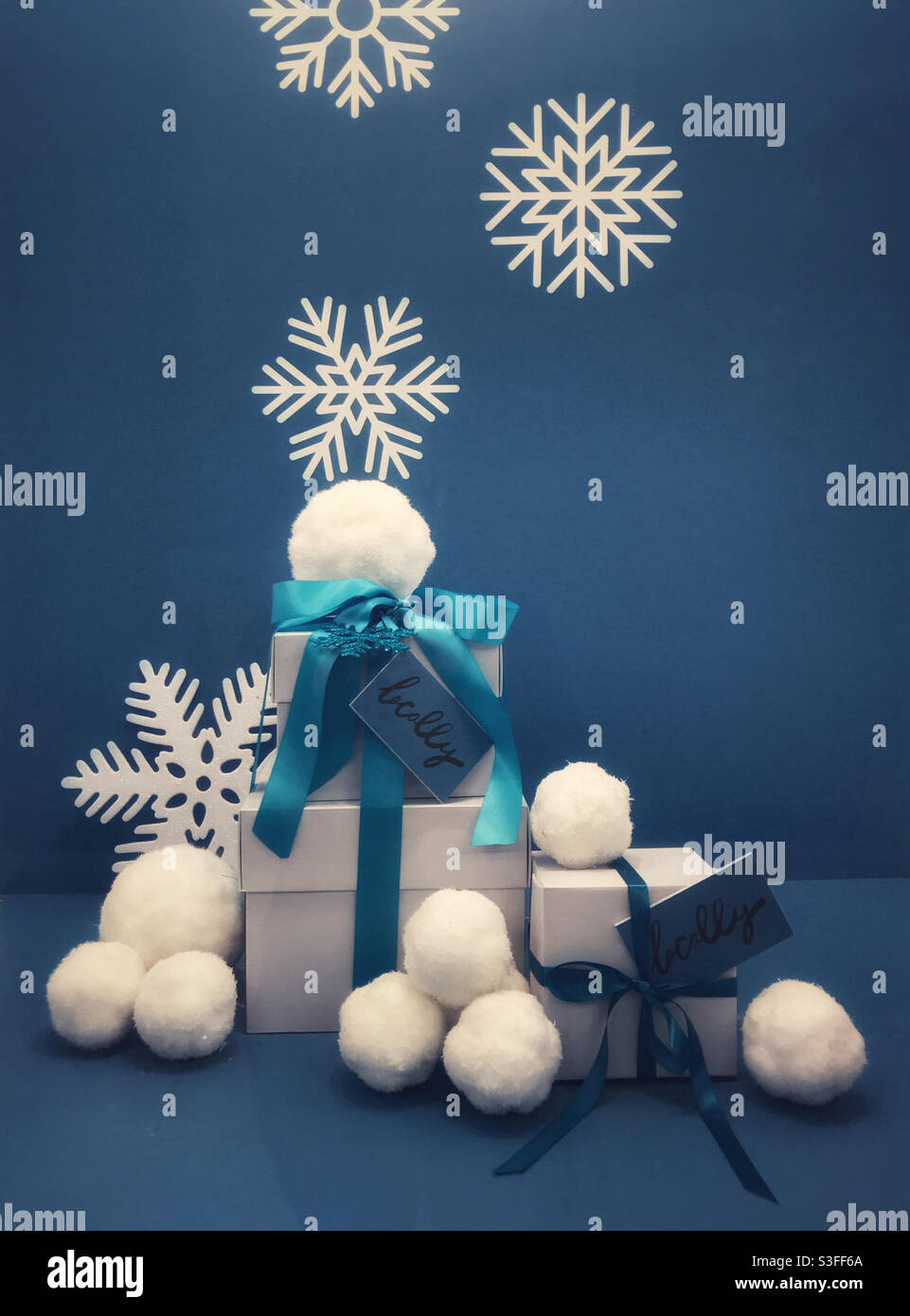 Arrangement bleu et blanc de cadeaux, boules de neige et flocons de neige sur un fond bleu. Afficher encourager les achats locaux. Banque D'Images