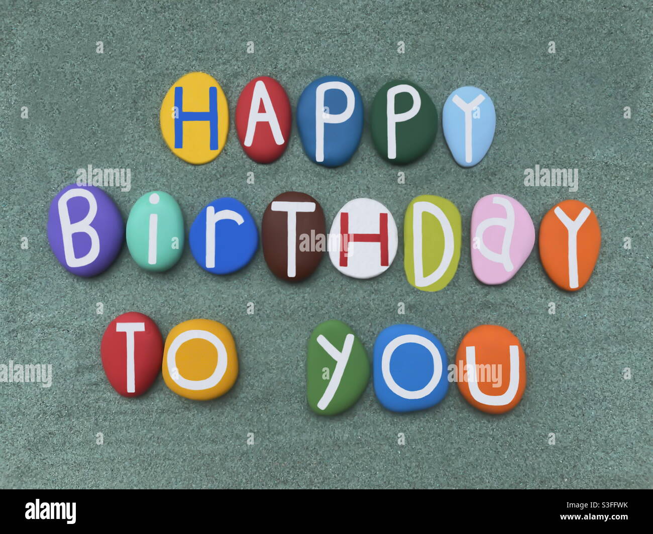 Joyeux Anniversaire A Vous Composition De Texte Creative Avec Des Lettres De Pierre Peintes A La Main Multicolores Sur Du Sable Vert Photo Stock Alamy