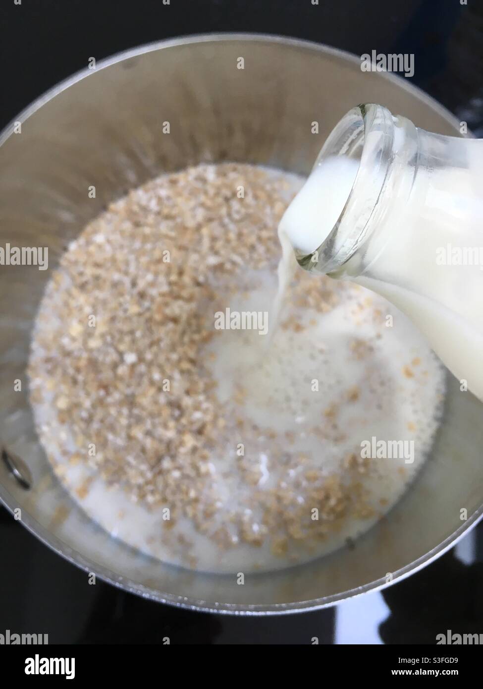 Le lait versé dans le biberon dans de l'avoine porridge Banque D'Images