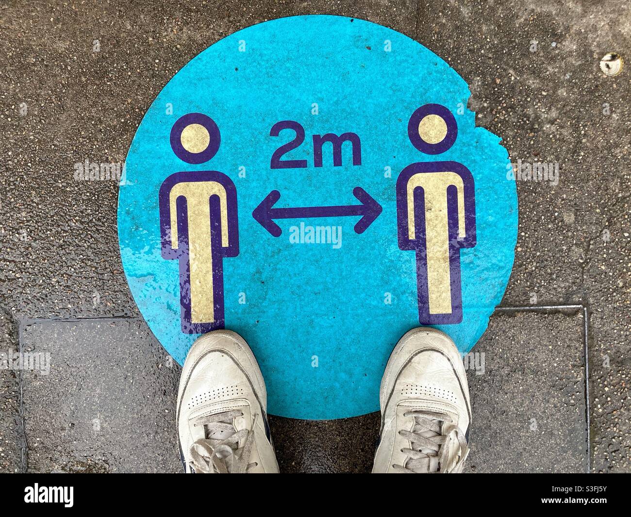 Social distance Sticker sur le sol avec deux sneakers Banque D'Images