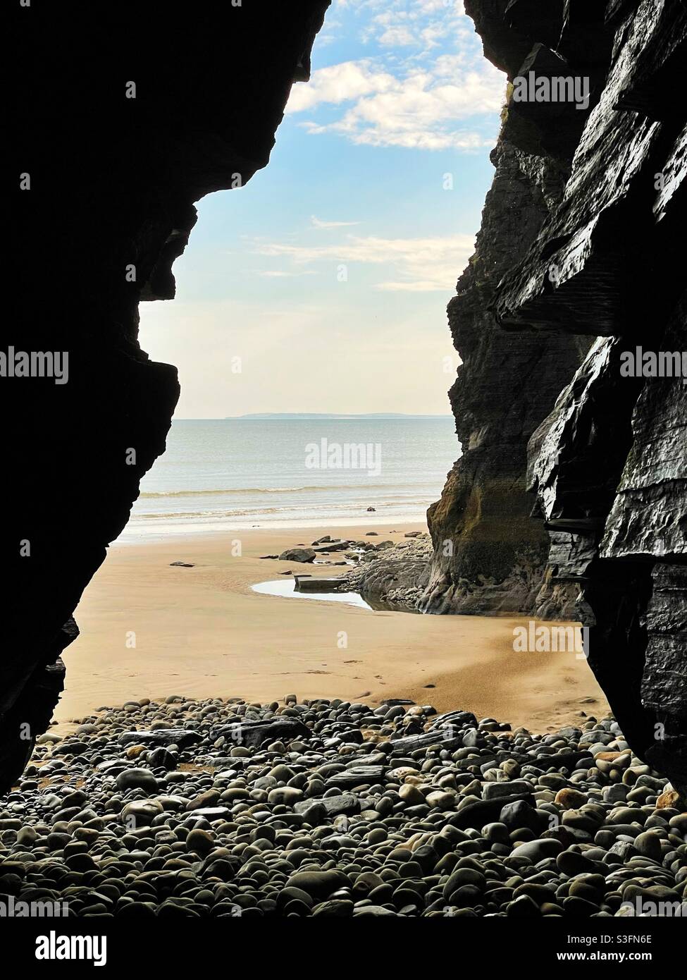 La mer, encadrée par l'ouverture d'une grotte de mer dans les falaises, pays de Galles du Sud, mai. Banque D'Images