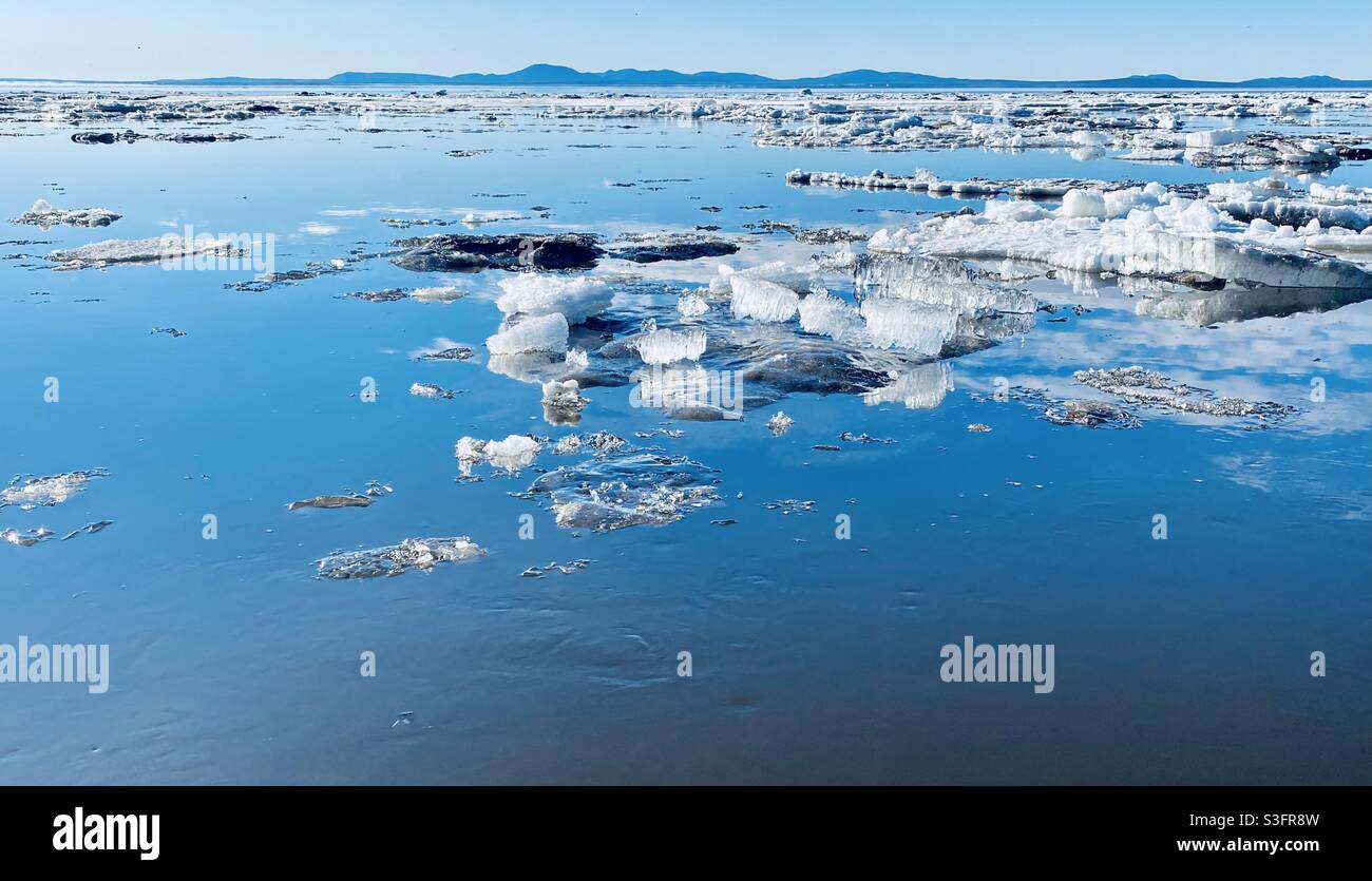 Floes de glace et cristaux de glace flottant dans le détroit de Kotzebue pendant la rupture annuelle au printemps de la glace de mer et de rivière dans l'Arctique de l'Alaska. Monument national du Cap Krutenstern en arrière-plan. Banque D'Images