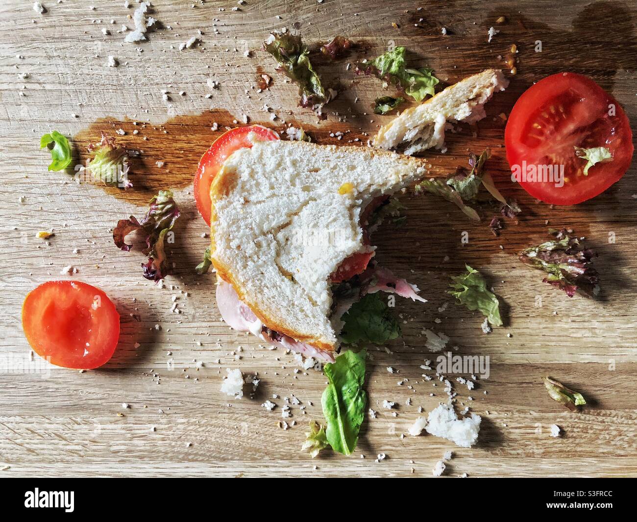 Les restes d'un sandwich à moitié mangé et d'une assiette désordonnée de nourriture Banque D'Images