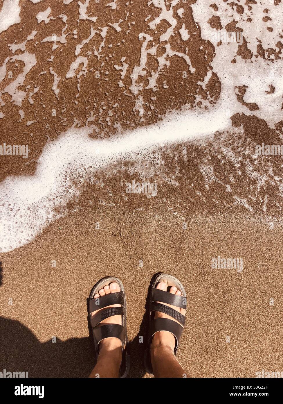 Homme dans des sandales debout près de la rive - Image de stock capturée avec un smartphone