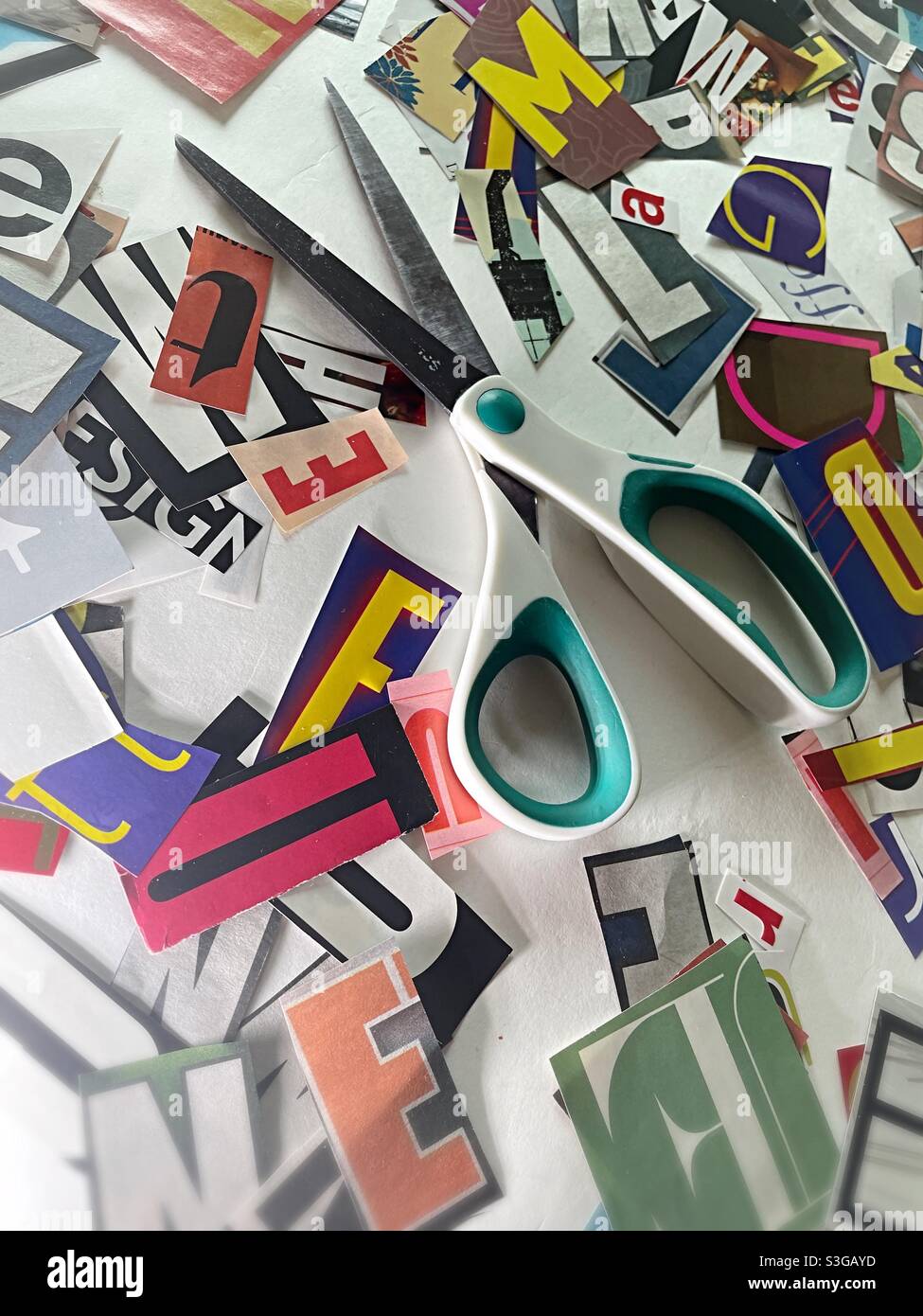 Des ciseaux et du papier ont découpé des lettres sur une surface de travail blanche, aux États-Unis - Image de stock capturée avec un smartphone