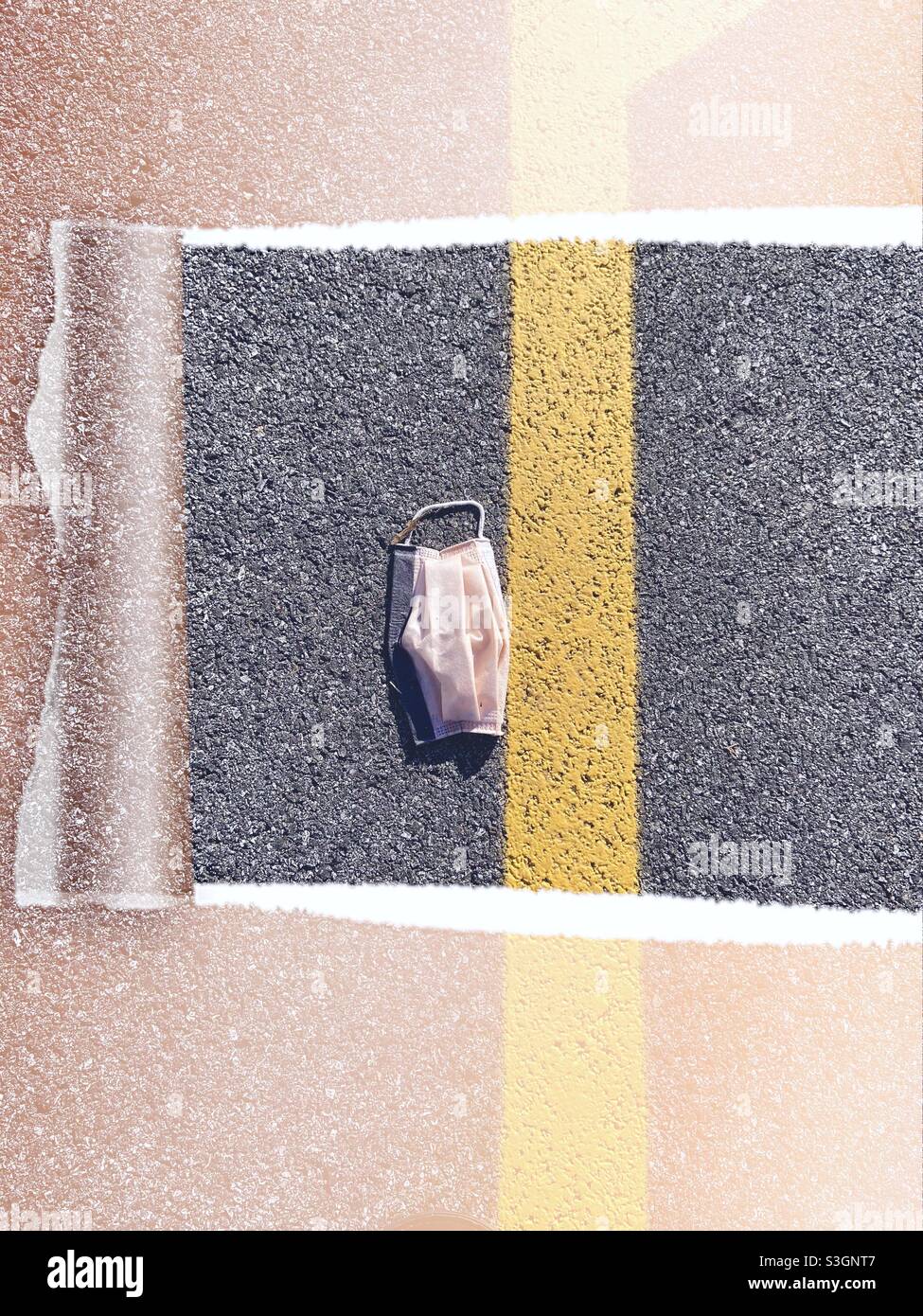 Masque médical en papier rose jeté au milieu d'une rue de ville. Double concept : les déchets de litière du coronavirus s'ajoutent à la crise climatique et se rouvrent également après les couleurs jaune et gris chaudes du COVID-19. - Image de stock capturée avec un smartphone