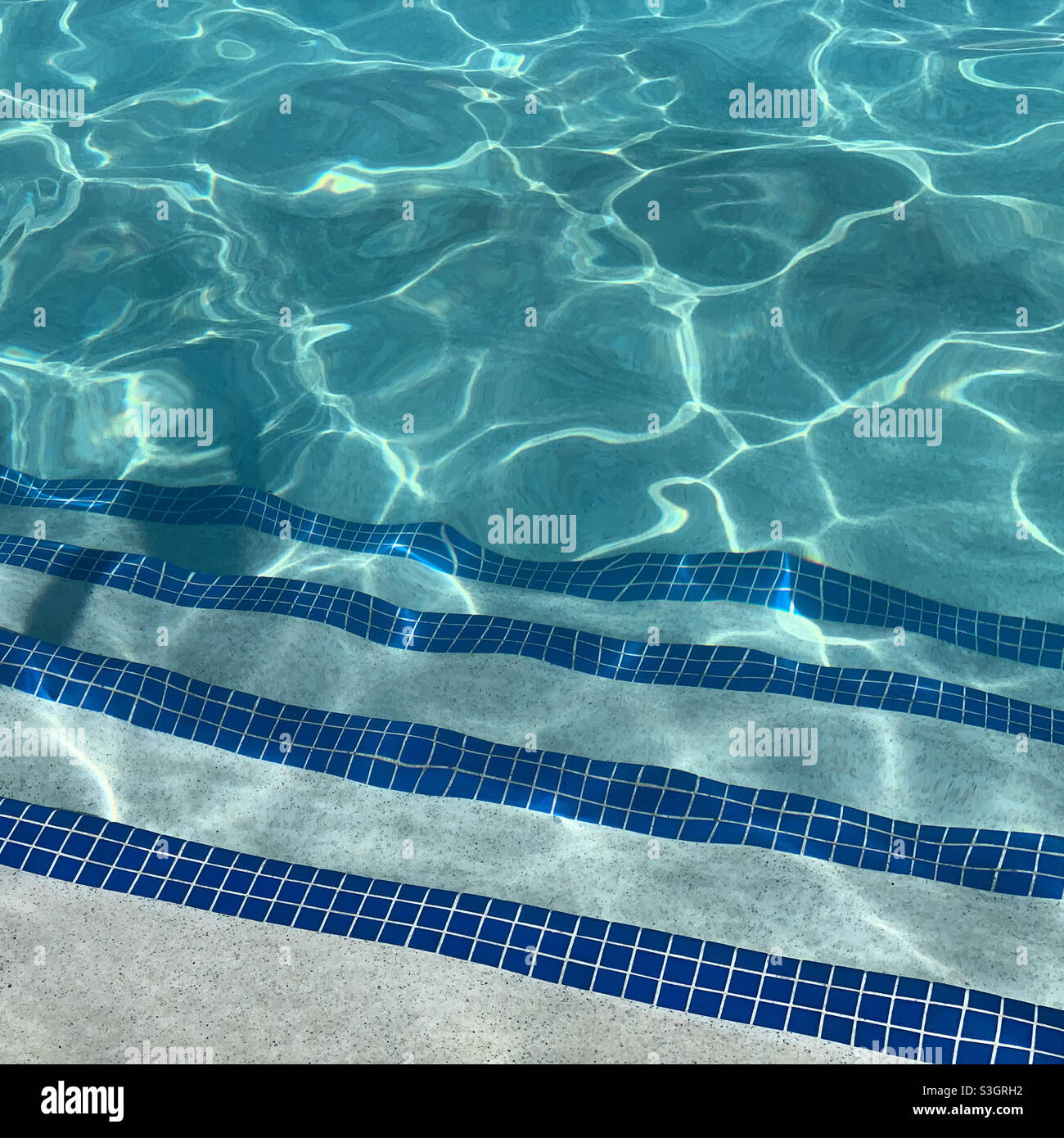 Des marches carrelées dans une piscine du complexe, le soleil se réfléchit sur l'eau - Image de stock capturée avec un smartphone