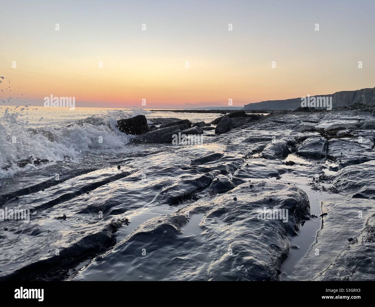 Vagues sur la côte sud du pays de Galles au crépuscule, juillet. Banque D'Images