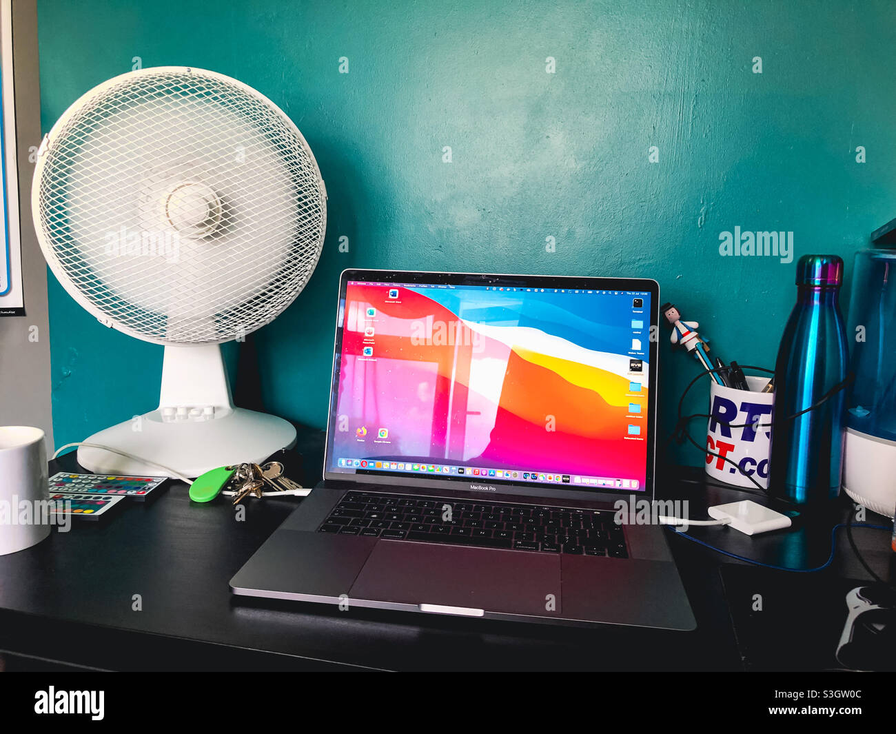 Un ventilateur de bureau à côté de l'ordinateur portable est un équipement important pour travailler à domicile pendant une vague de chaleur au Royaume-Uni. - Image de stock capturée avec un smartphone