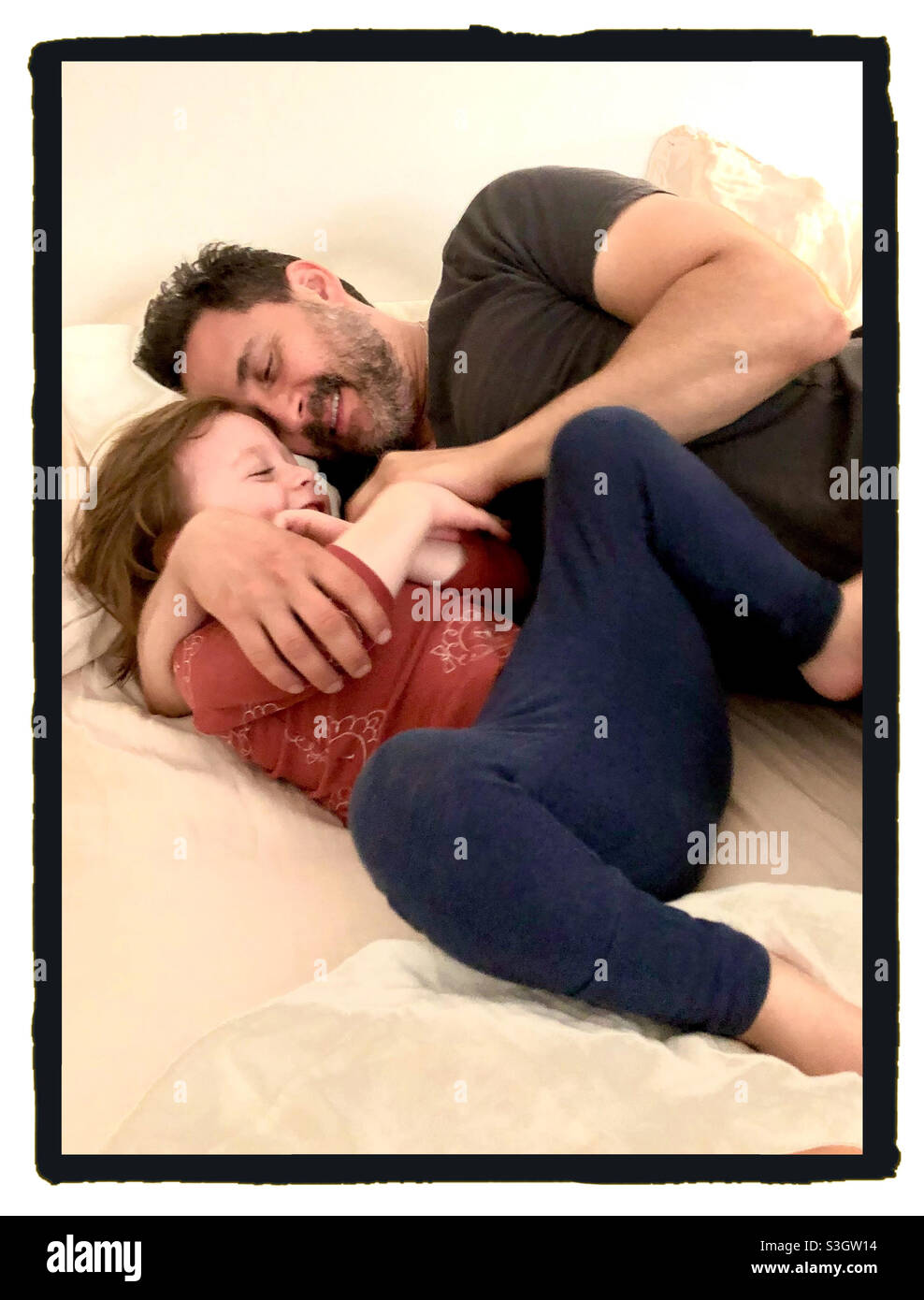 Le père et le fils tout-petits rient et se câlinent chez eux. - Image de stock capturée avec un smartphone