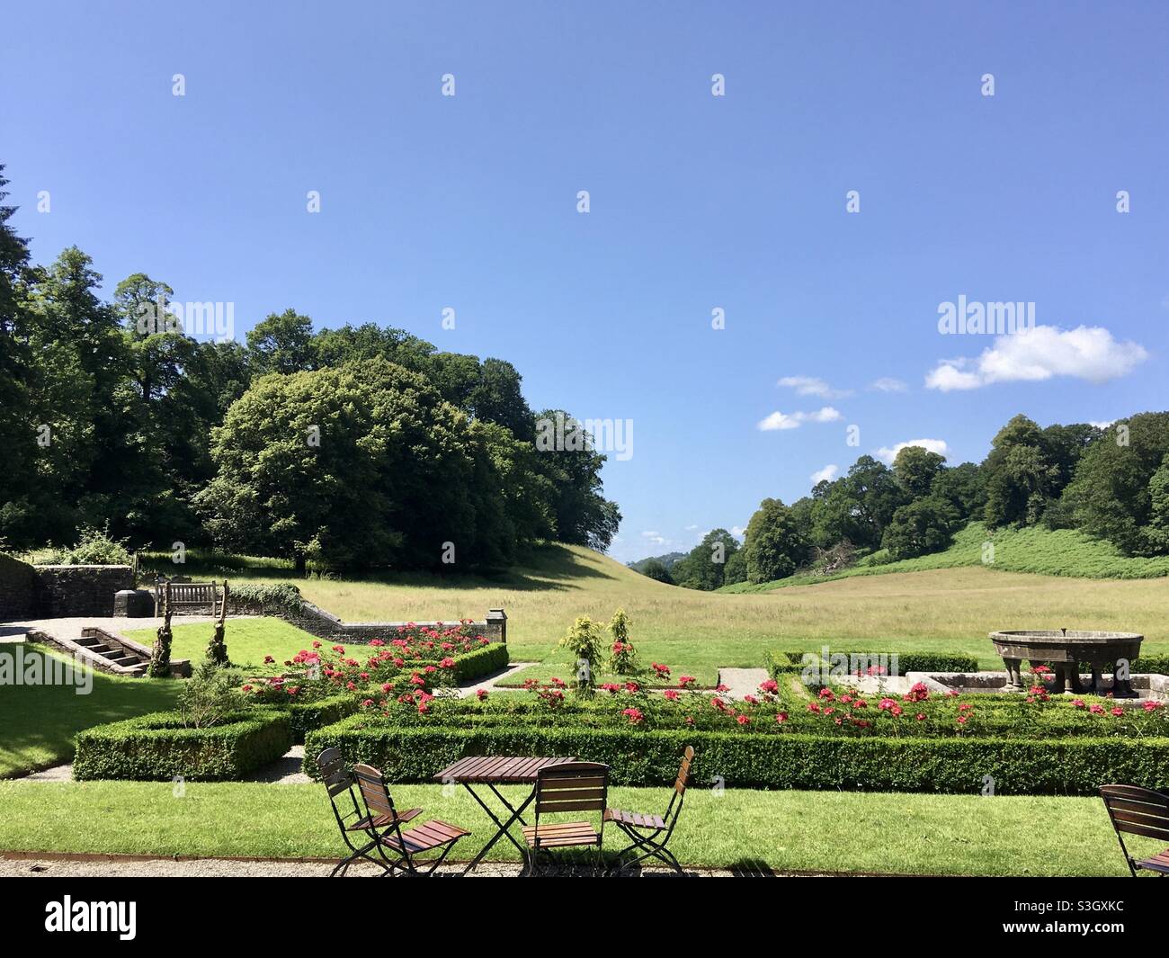 Tables et chaises sur une terrasse donnant sur un jardin de roses et un parc Banque D'Images