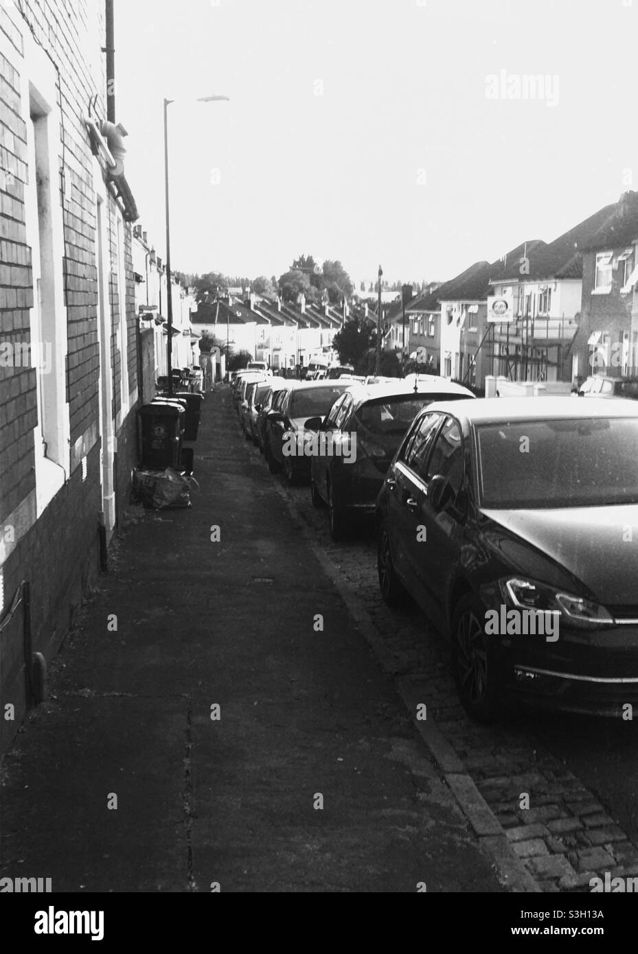 Une rue résidentielle dans la ville de Bristol, Angleterre, Royaume-Uni, en juillet 2021. Photo en noir et blanc montrant des maisons mitoyennes et des voitures garées Banque D'Images