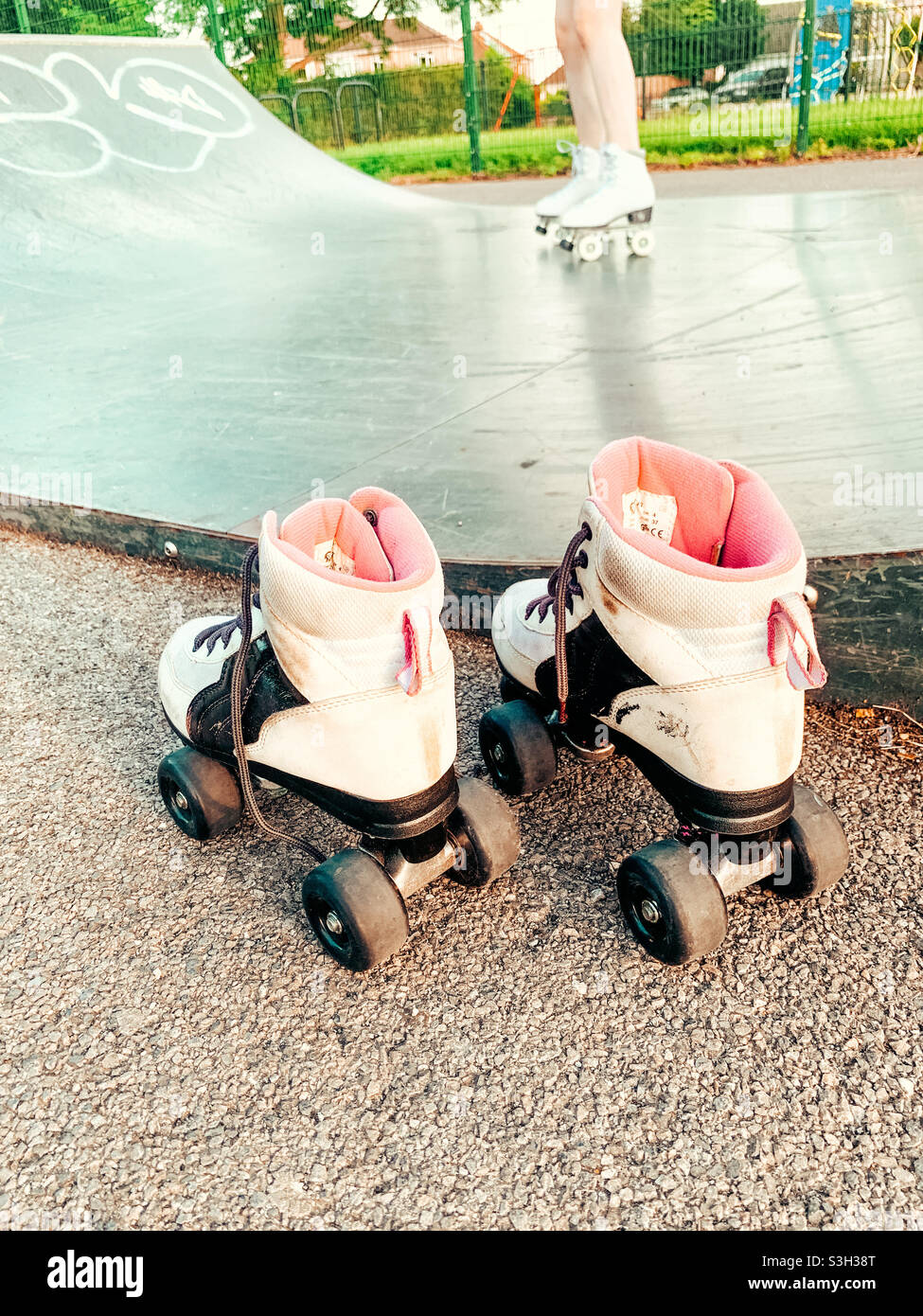 Une paire de patins à roulettes et une jeune femme patinant en arrière-plan Banque D'Images