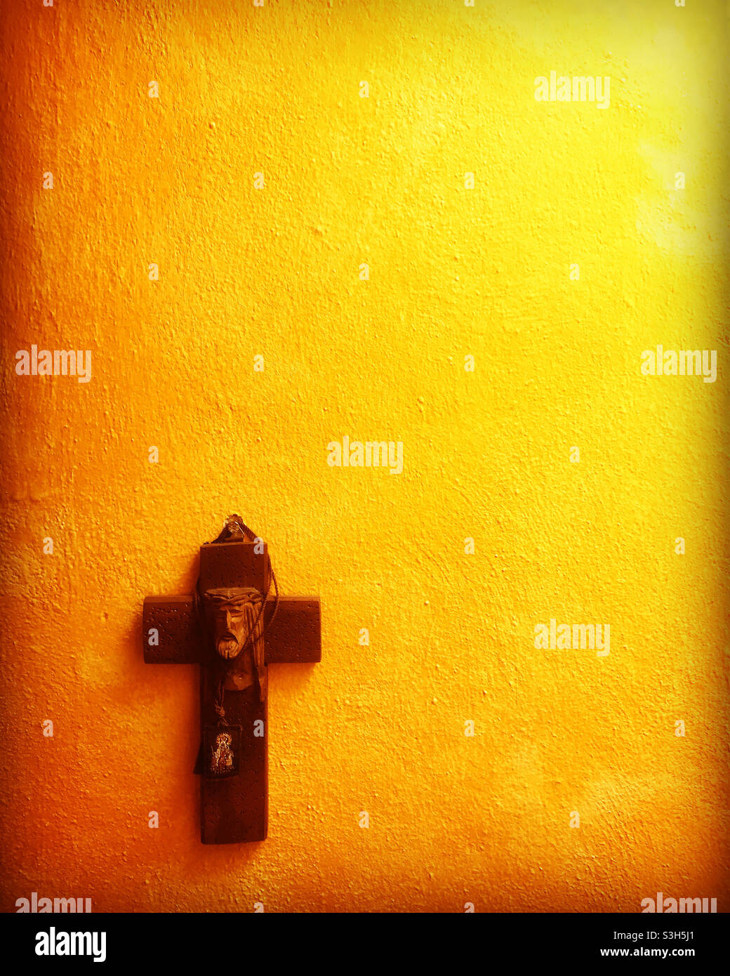 Un crucifix en bois avec le visage de Jésus-Christ sur un mur jaune à Peña de Bernal, Queretaro, Mexique Banque D'Images