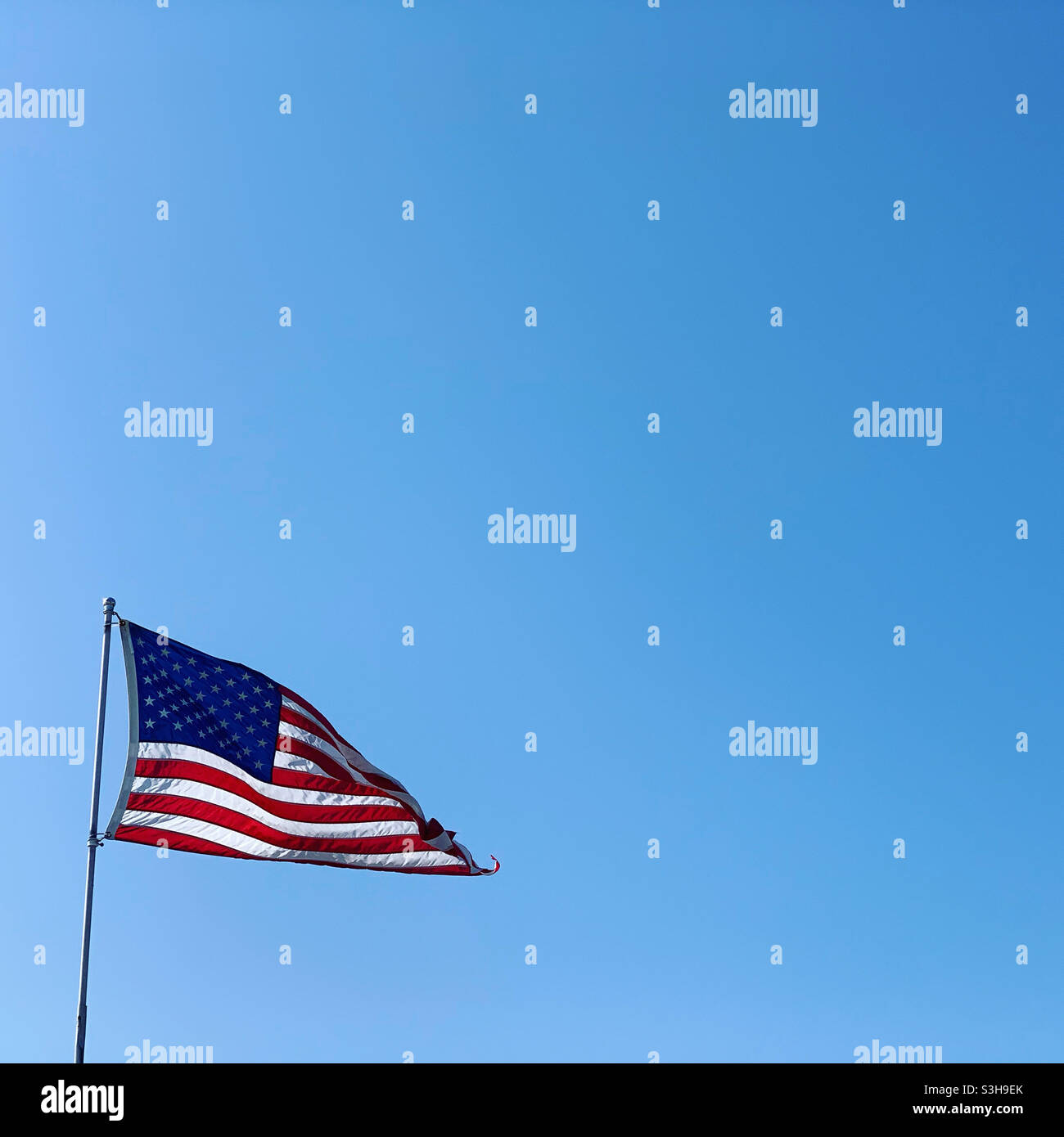 Drapeau américain dans le vent devant un ciel bleu Banque D'Images
