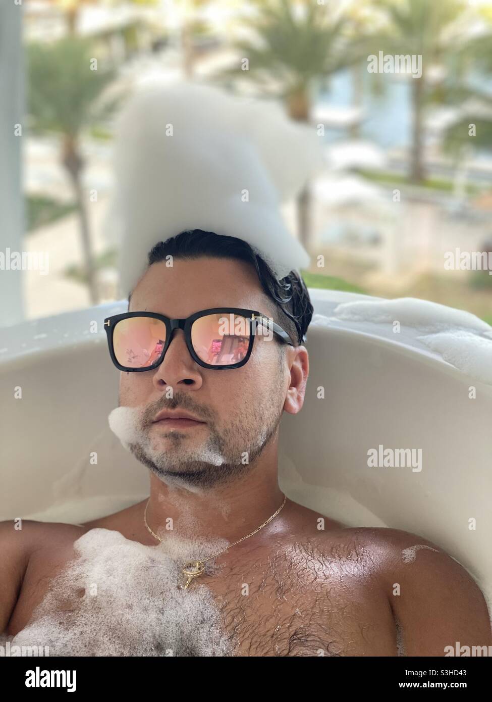 Homme portant des lunettes de soleil dans un bain à bulles extérieur Banque D'Images
