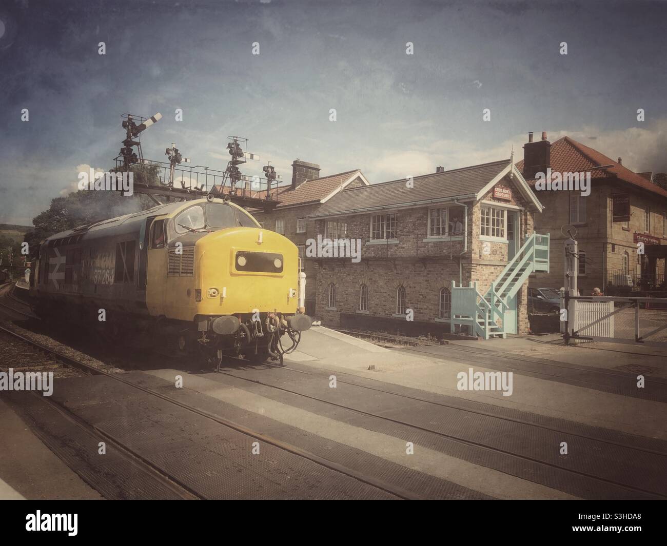 Un vintage. Image d'une locomotive diesel de classe 37 se déplaçant à travers le passage à niveau sur la ligne de chemin de fer historique de Grosmont dans le chemin de fer de North Yorkshire Moors Banque D'Images