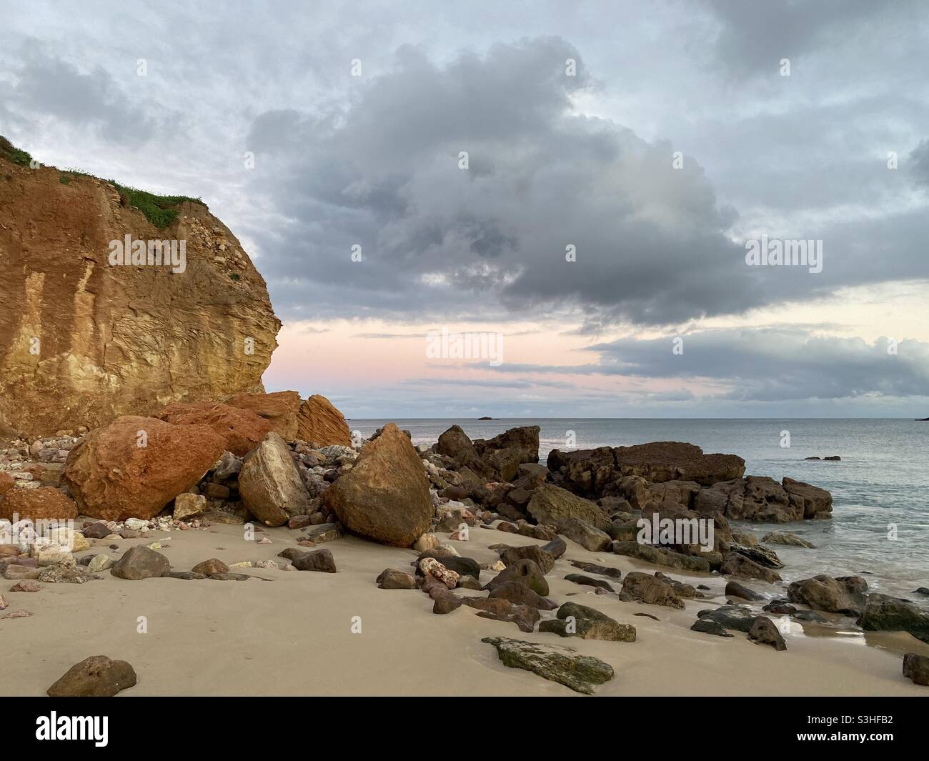 Rochers tombés sur une plage de sable au crépuscule - Image de stock capturée avec un smartphone