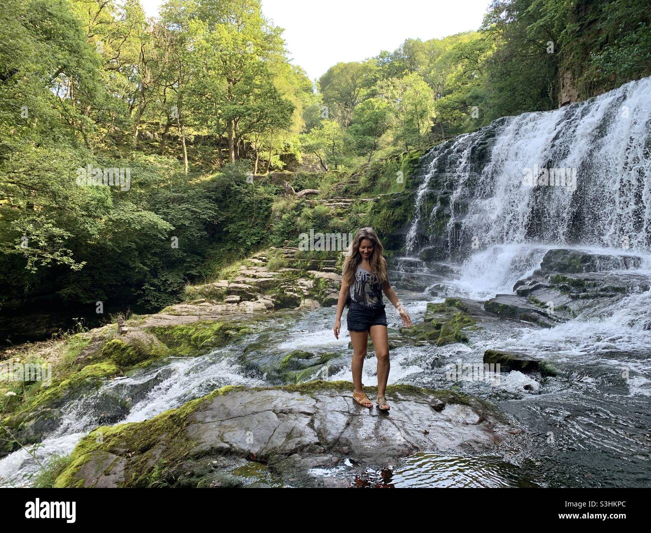 Femme marchant sur des rochers en cascade à la sgwd clun-gwyn à Brecon Sud-Galles - Image de stock capturée avec un smartphone
