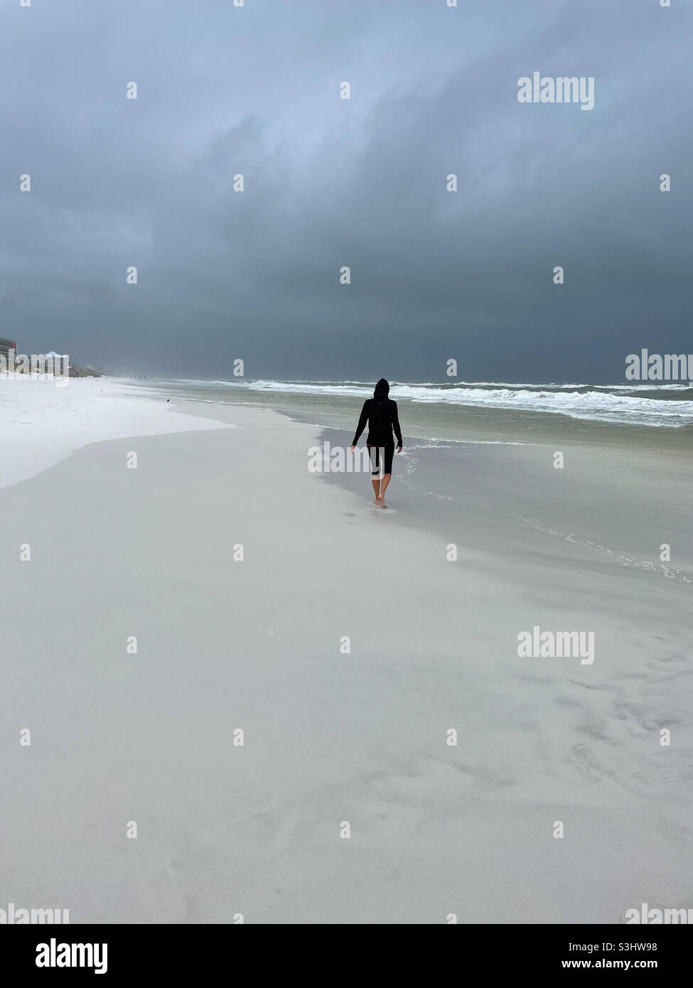 Femme isolée marchant sur la plage de Panhandle de Floride pendant les tempêtes de bande extérieure de l'ouragan Ida Banque D'Images