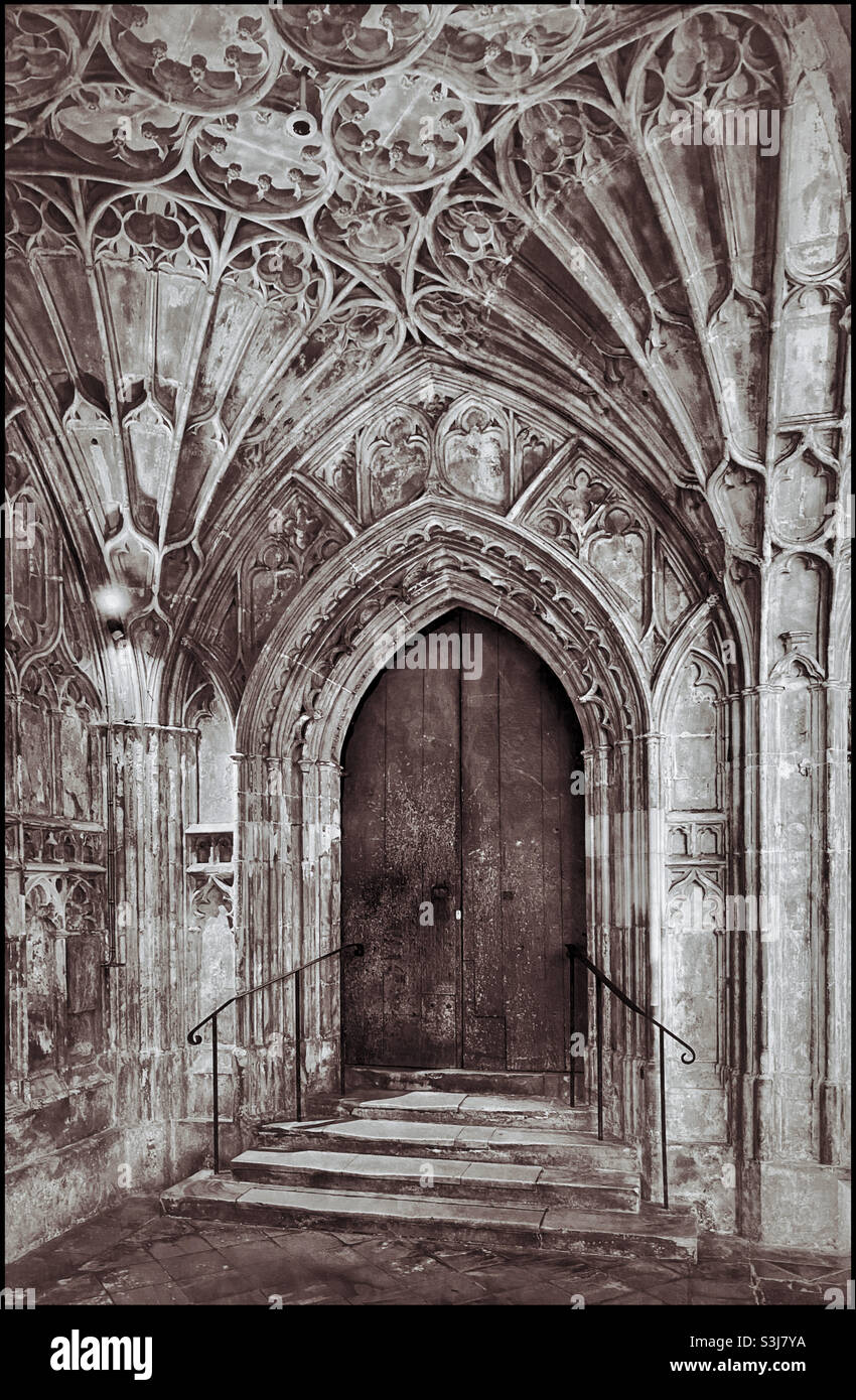 Une porte en bois sépare la zone des cloîtres de la section principale de la cathédrale de Gloucester. Cette zone a été utilisée dans le tournage de 2 films Harry Potter. Le plafond voûté du ventilateur est une attraction majeure. ©️ - Image de stock capturée avec un smartphone