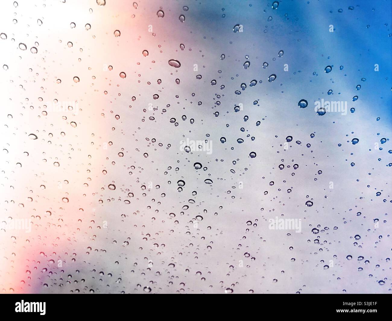 Gouttes de pluie sur verre avec ciel coloré Banque D'Images