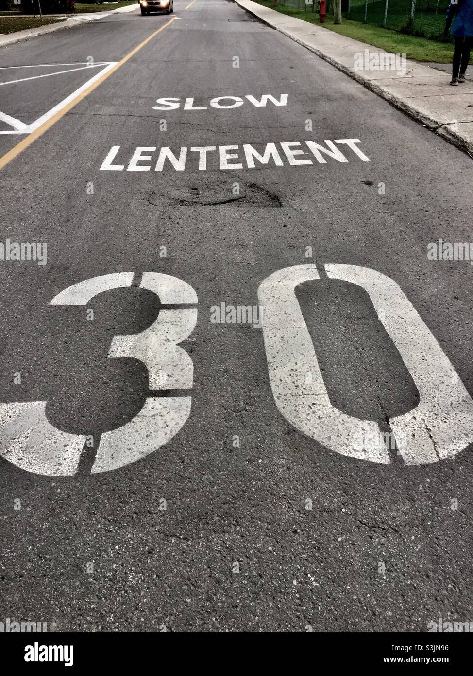 Panneau de vitesse sur la route en deux langues, anglais et français.Canada.Lent.Vitesse maximale de 30 kilomètres par heure.La voiture approche. - Image de stock capturée avec un smartphone