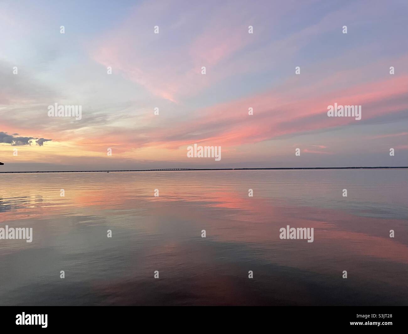 Ciel doux de coucher de soleil rose et orange pastel se reflétant sur l'eau de la baie calme Banque D'Images
