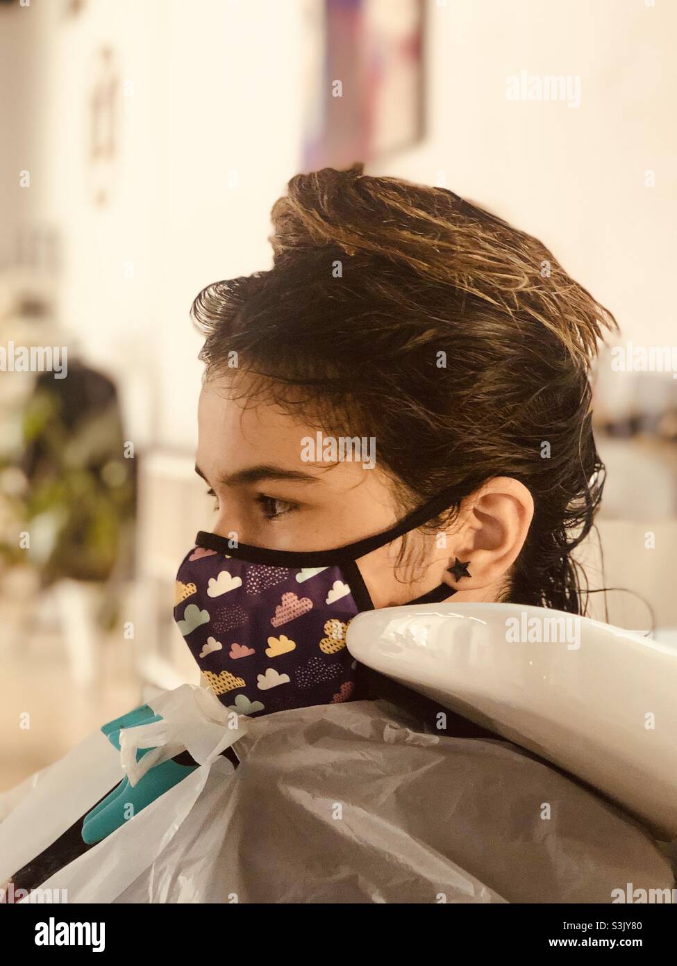 fille de 13 ans au salon de coiffure avec un masque violet pour le covid Banque D'Images